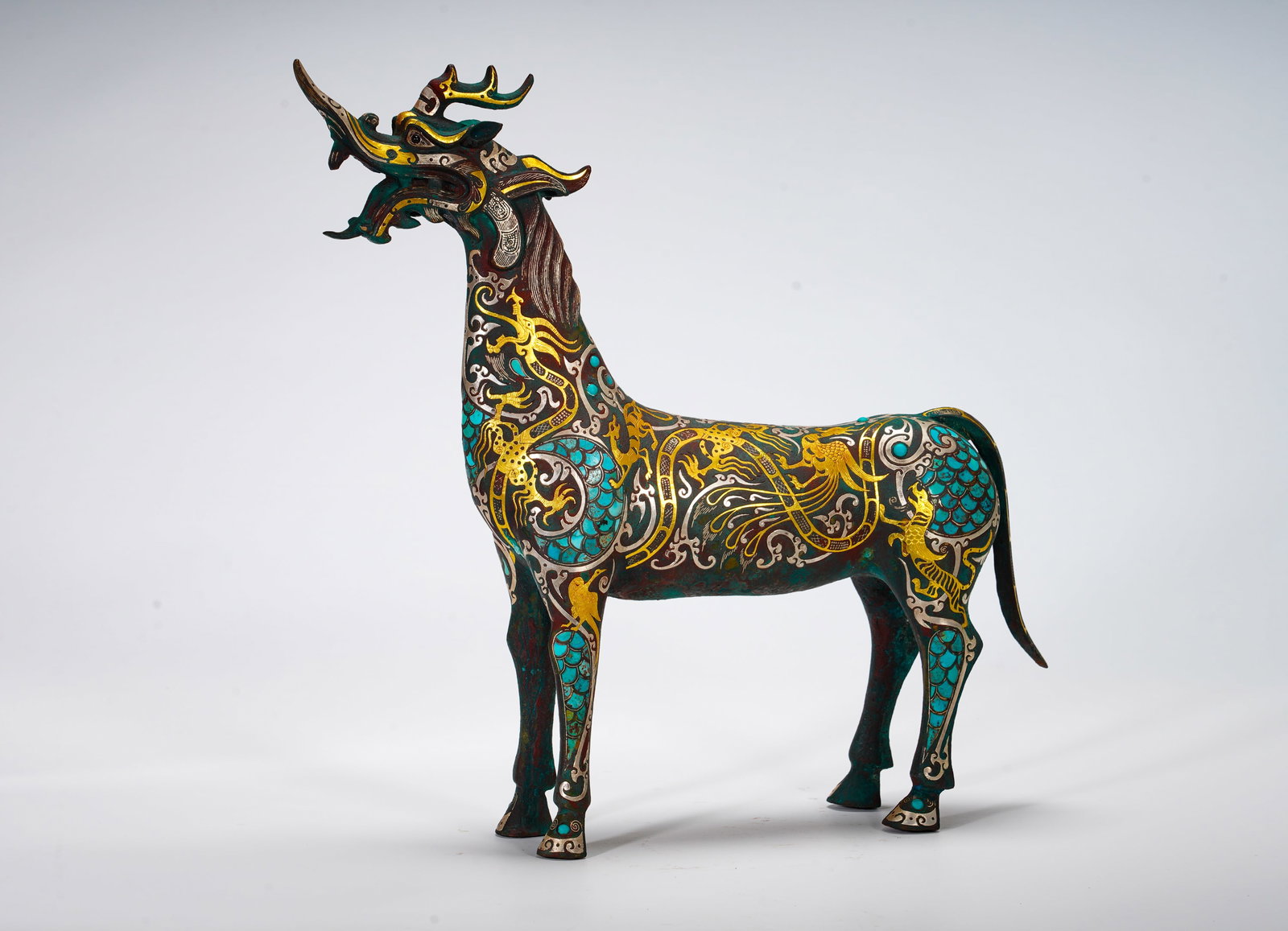 BRONZE INLAID WITH GOLD AND SILVER MYTHICAL BEAST FROM THE WARRING STATES PERIOD: Height:34cm (13.39in) Width:34cm (13.39in) Weight:2040g(4.50lb)Bronze statue of dragon-headed horse, legendary celestial auspicious beast. Surface decorated with phoenix and tiger scrolls in gold and 