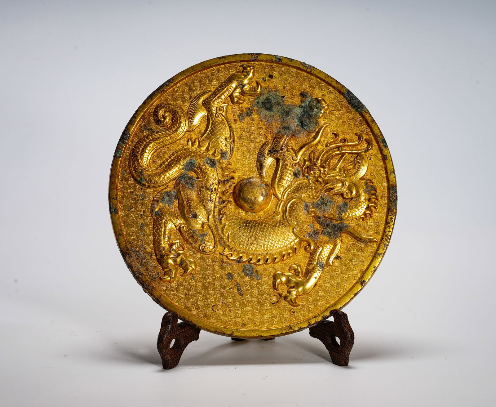 BRONZE GILDED DOUBLE DRAGON PLAYING WITH A PEARL MIRROR OF THE TANG DYNASTY: Diameter:19.7cm (7.76in) Weight:1950g(4.30lb)Gilded circular bronze relic embossed with confronting dragon pair and central pearl. Wave pattern background. Dragon symbolizes celestial auspicious beast