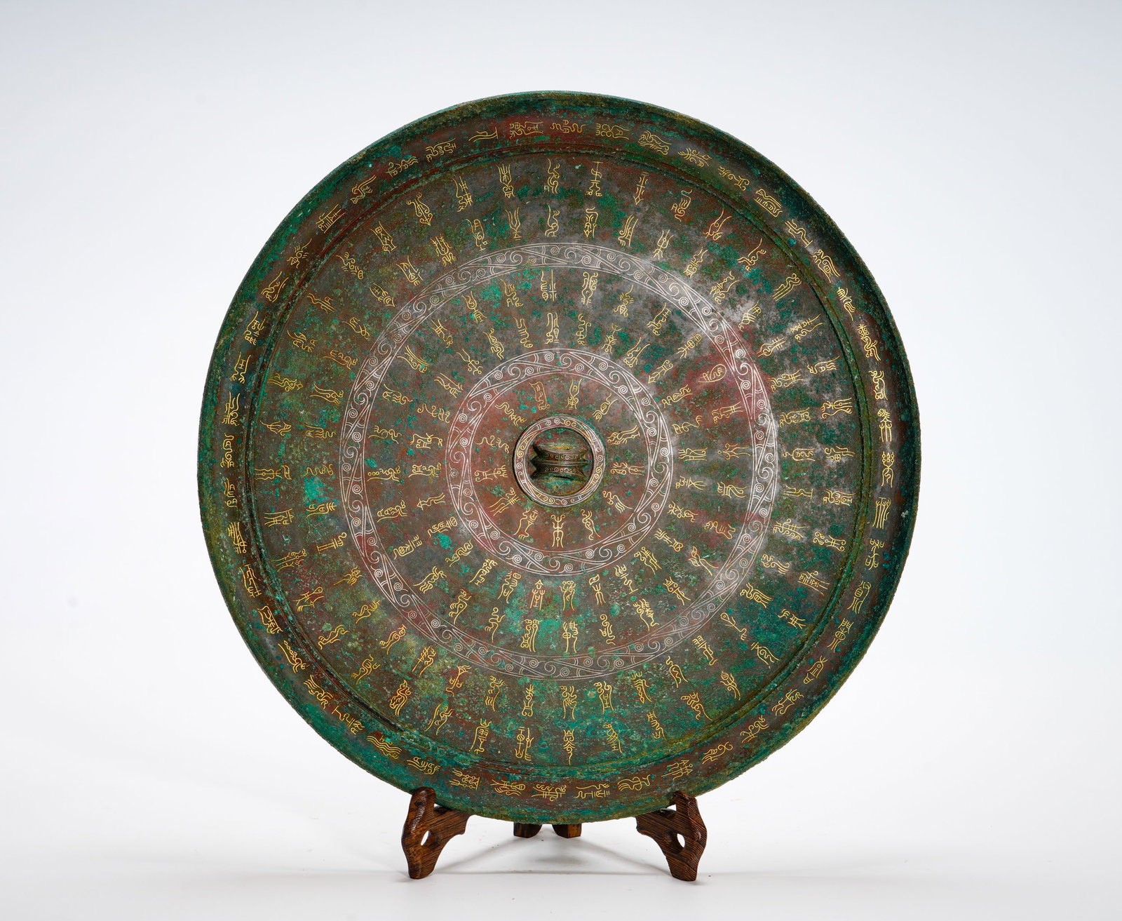 BRONZE INLAID WITH GOLD AND ENGRAVED WITH BIRD SCRIPT MIRROR OF THE HAN DYNASTY: Diameter:31cm (12.20in) Weight:1940g(4.28lb)Round bronze mirror with multi-ring layout on reverse. Golden wire carved archaic bird-shaped seal characters, silver cloud dividing lines. Bird-insect call