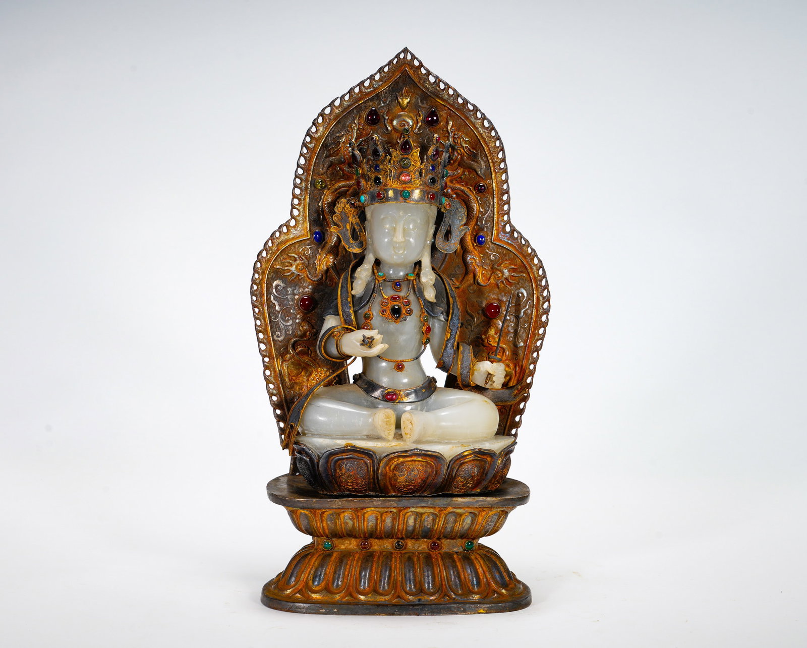 A SILVER-GILDED WHITE JADE INLAID MANJUSRI BODHISATTVA STATUE FROM THE MING DYNASTY: Height:33cm (12.99in) Width:19cm (7.48in) Weight:2570g(5.67lb)Jade Bodhisattva seated on lotus throne. Wearing jeweled crown and neck ornaments, holding vajra and sutra scroll. Gilded openwork dragon 