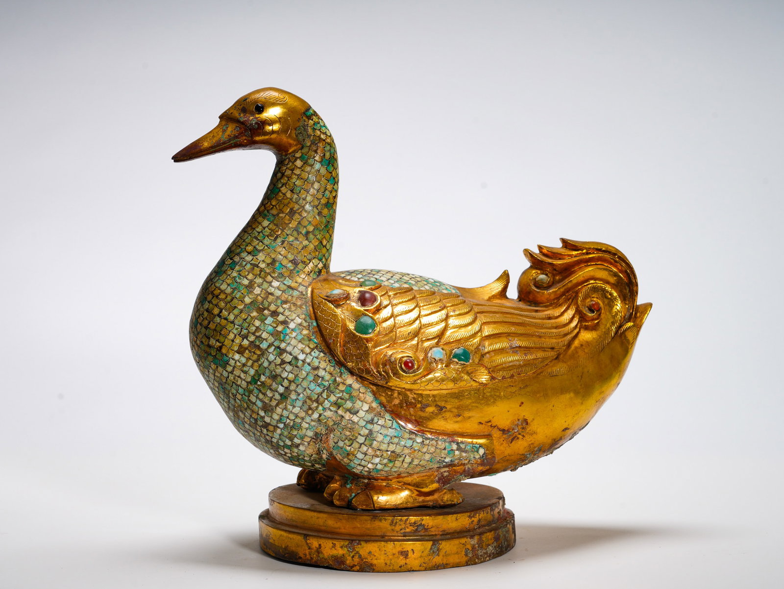 BRONZE VASE WITH GILDED TURQUOISE INLAID DUCK FROM THE TANG DYNASTY: Height:34cm (13.39in) Width:36cm (14.17in) Weight:6330g(13.95lb)Gilded bronze vessel modelled as standing duck. Turquoise mosaic forms feather texture, gemstone inlaid wings. Duck symbolizes peace and