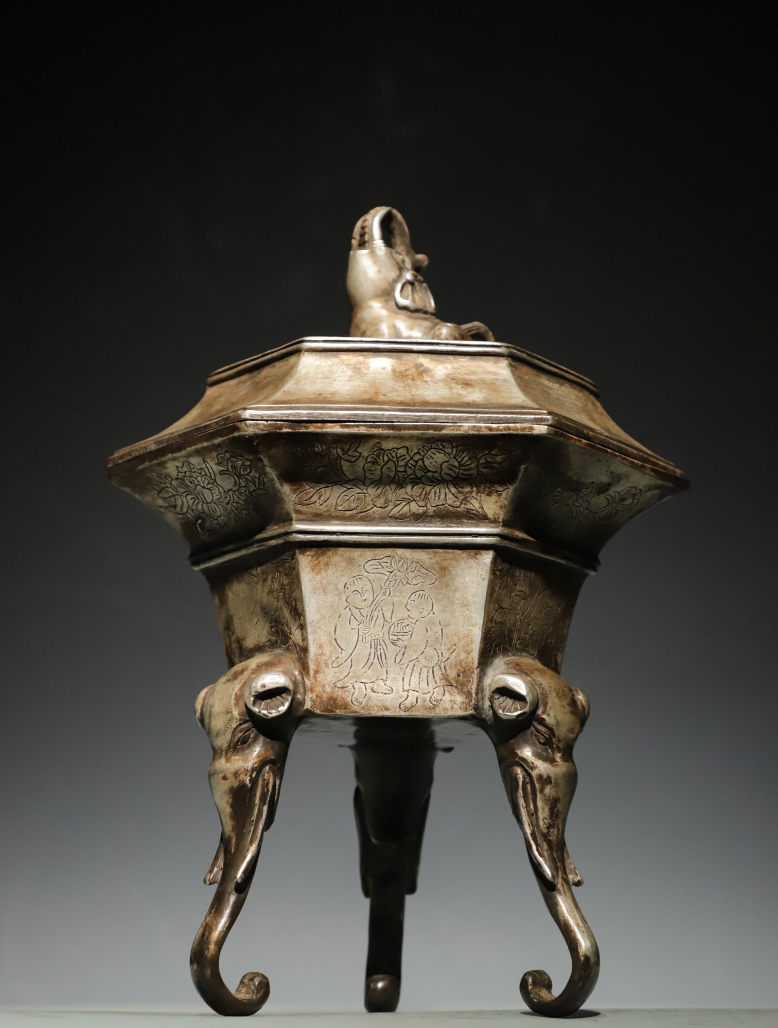 BRONZE HIGH-RELIEF ENGRAVED SILVER THREE-LEGGED INCENSE BURNER OF THE MING DYNASTY: Weight:1300g(2.87lb);H:26cm (10.24in) L:19cm (7.48in) W:13cm (5.12in)A hexagonal white copper censer with carved patterns and three elephant-head feet, topped with an elephant finial, fully engraved w