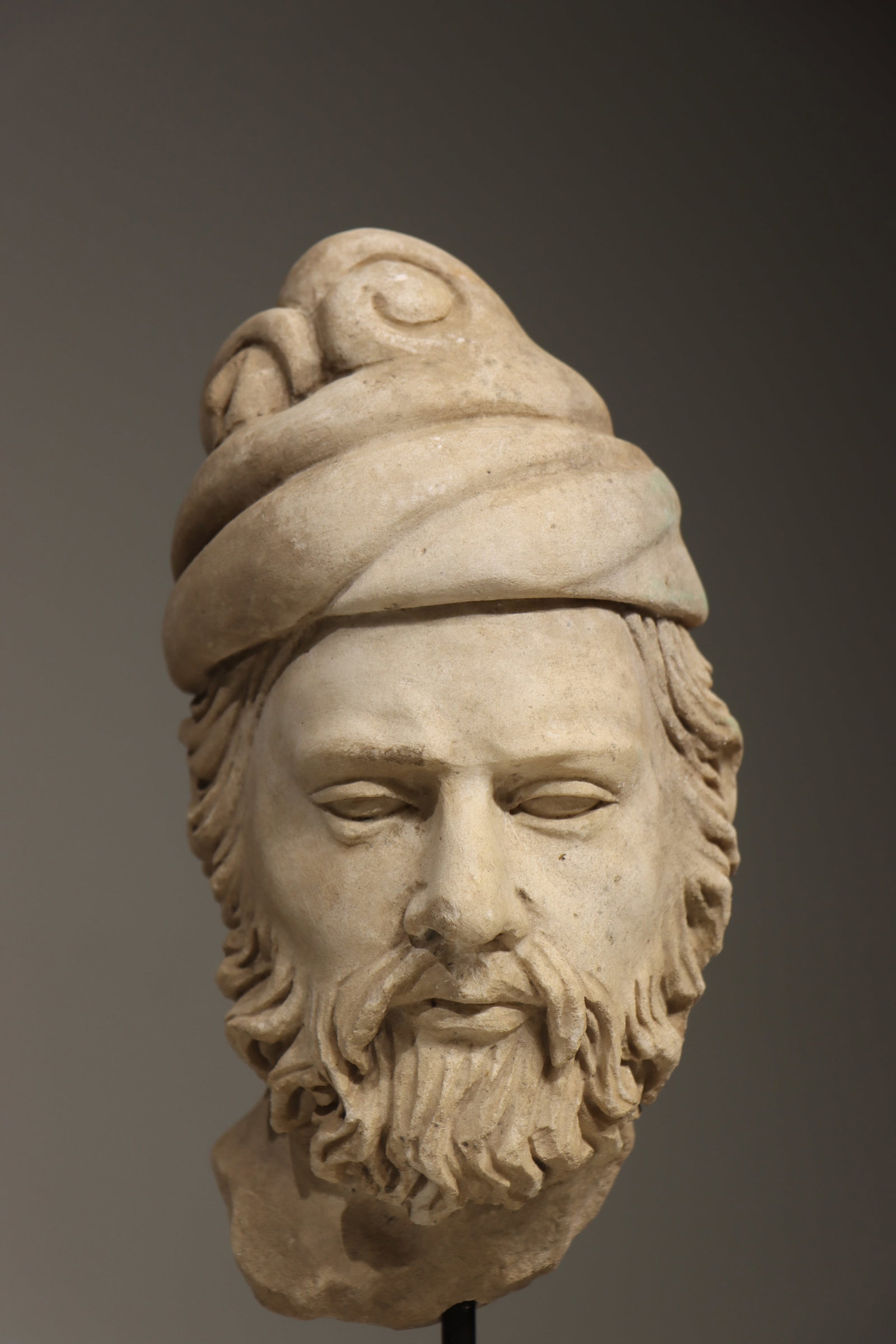 A 6TH-CENTURY GANDHARA STONE CARVING OF THE HEAD OF SAKYAMUNI BUDDHA: Total height 43 cm (16.93in), net height 24 cm (9.45in)