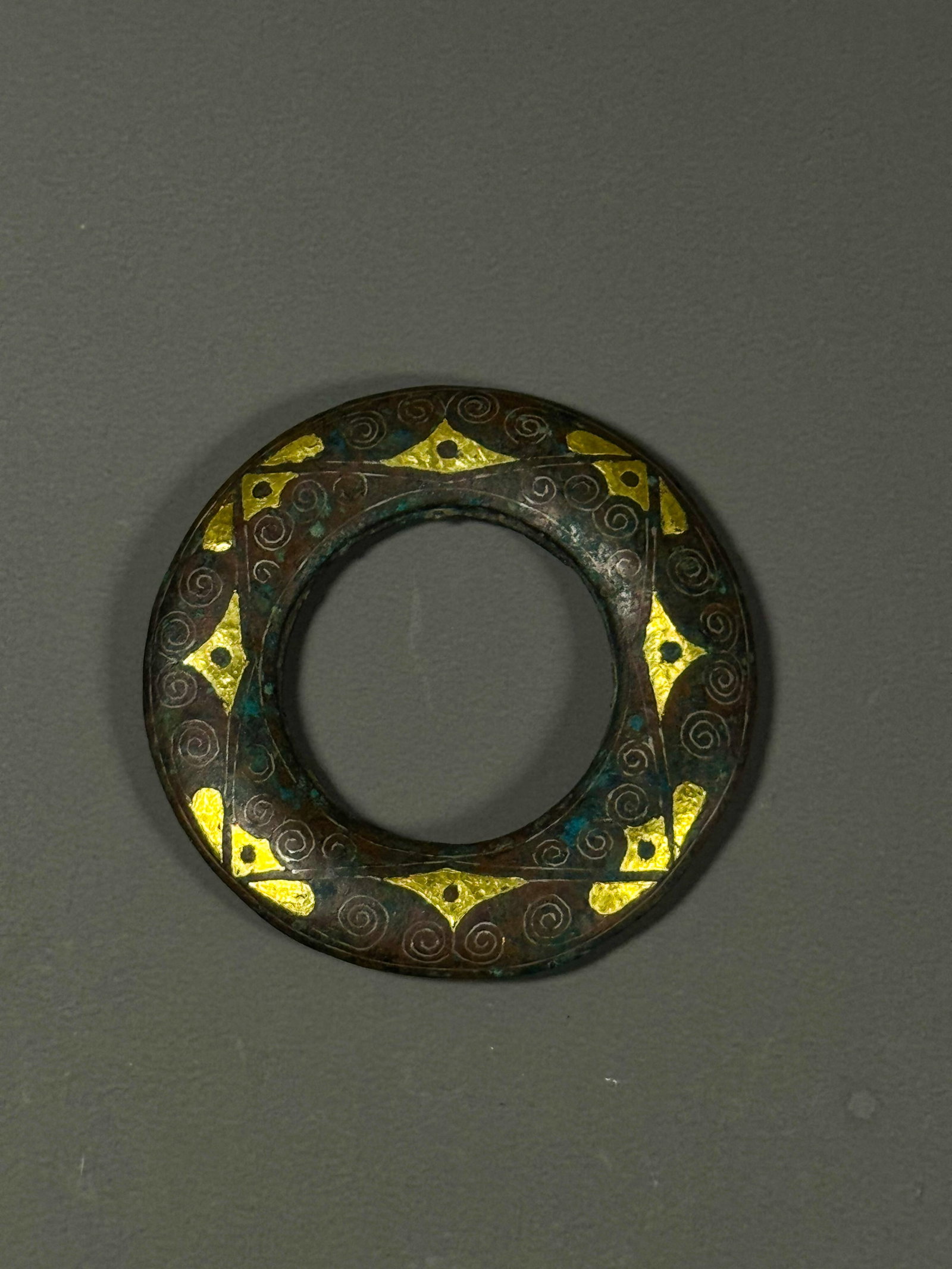 BRONZE FROM THE WARRING STATES PERIOD WITH GOLD INLAID VOLUTE PATTERNS: Diameter: 7cmWeight:118gWarring States Period, Bronze Ring with Gold Inlaid Spiral Pattern.This flat circular bronze ornament was for ancient nobles. Decorated with regularly arranged gold diamond