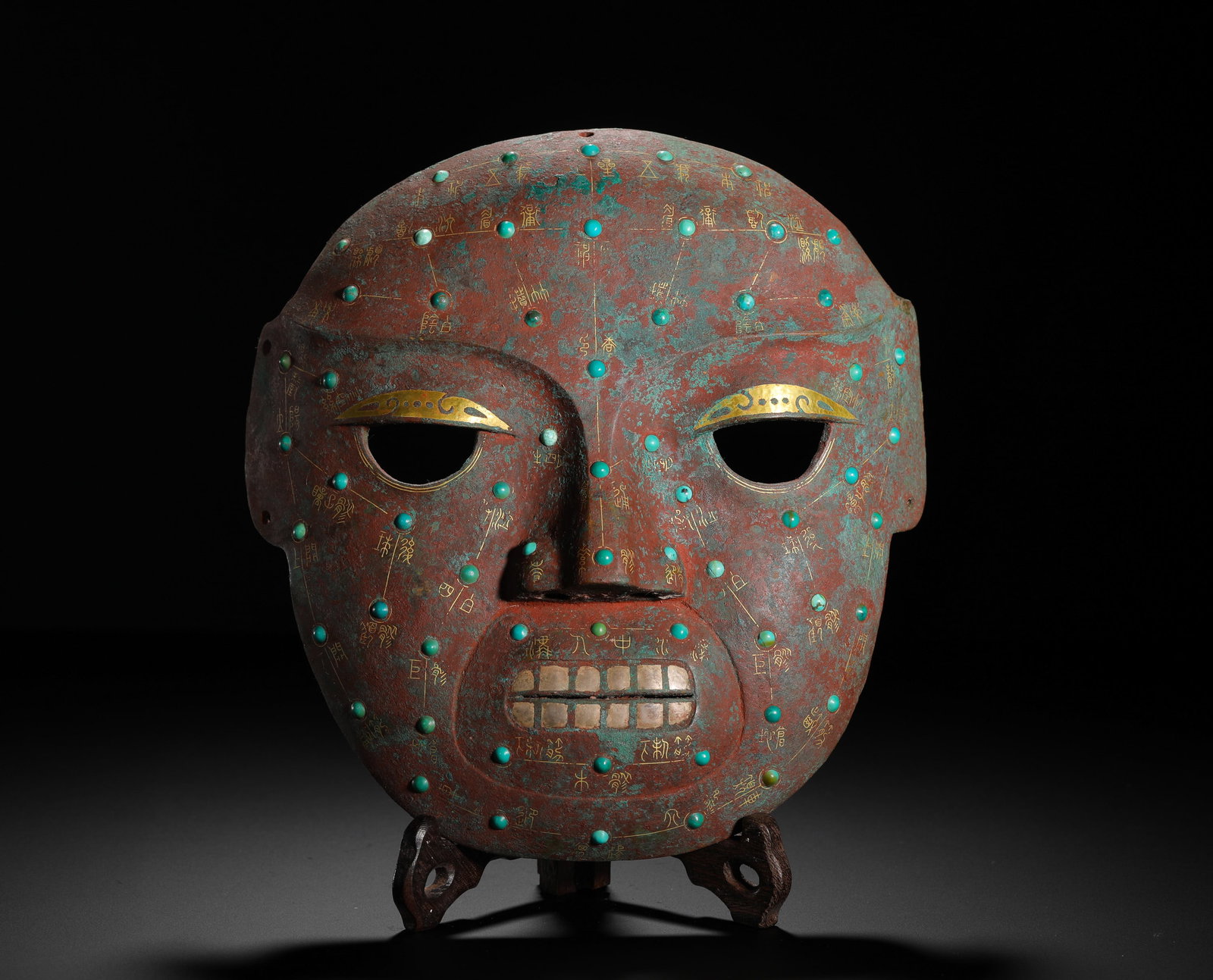 HAN DYNASTY BRONZE INLAID WITH GOLD AND TURQUOISE CHINESE ACUPUNCTURE HUMAN FACE MASK: H:23cm (9.06in) W:22cm (8.66in) Weight:830g (1.83lb)Archaic bronze facial mask with gold-inlaid acupuncture meridian texts, turquoise studs marking acupoints.