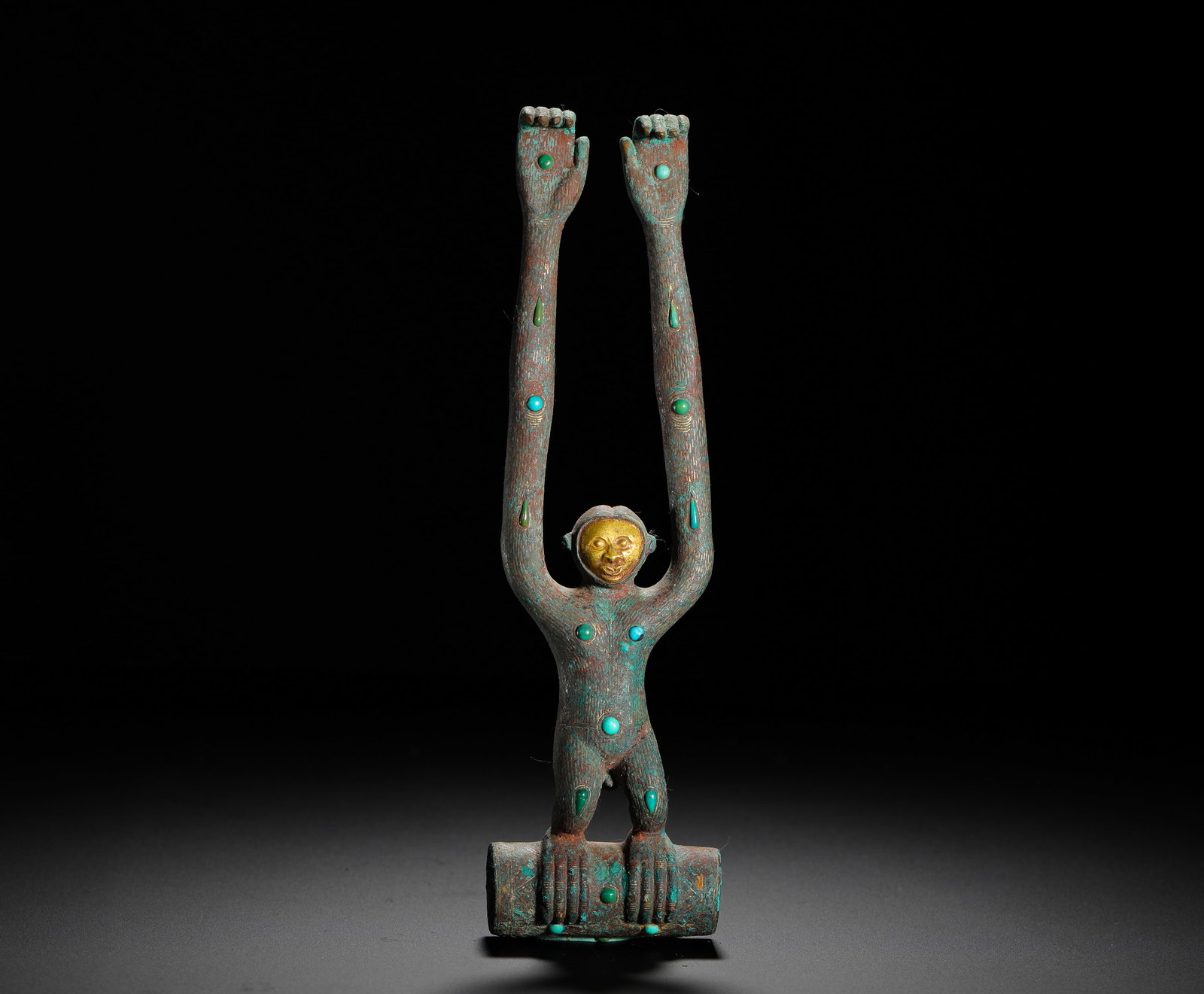 BRONZE GILDED HUMAN FACE INLAID WITH TURQUOISE MONKEY STAFF HEAD OF THE QIN DYNASTY: H:22.5cm (8.86in) W:6cm (2.36in) Weight:570g (1.26lb)Bronze monkey-shaped staff finial, gilded face, body studded with turquoise beads, cylindrical socket at feet for cane shaft.