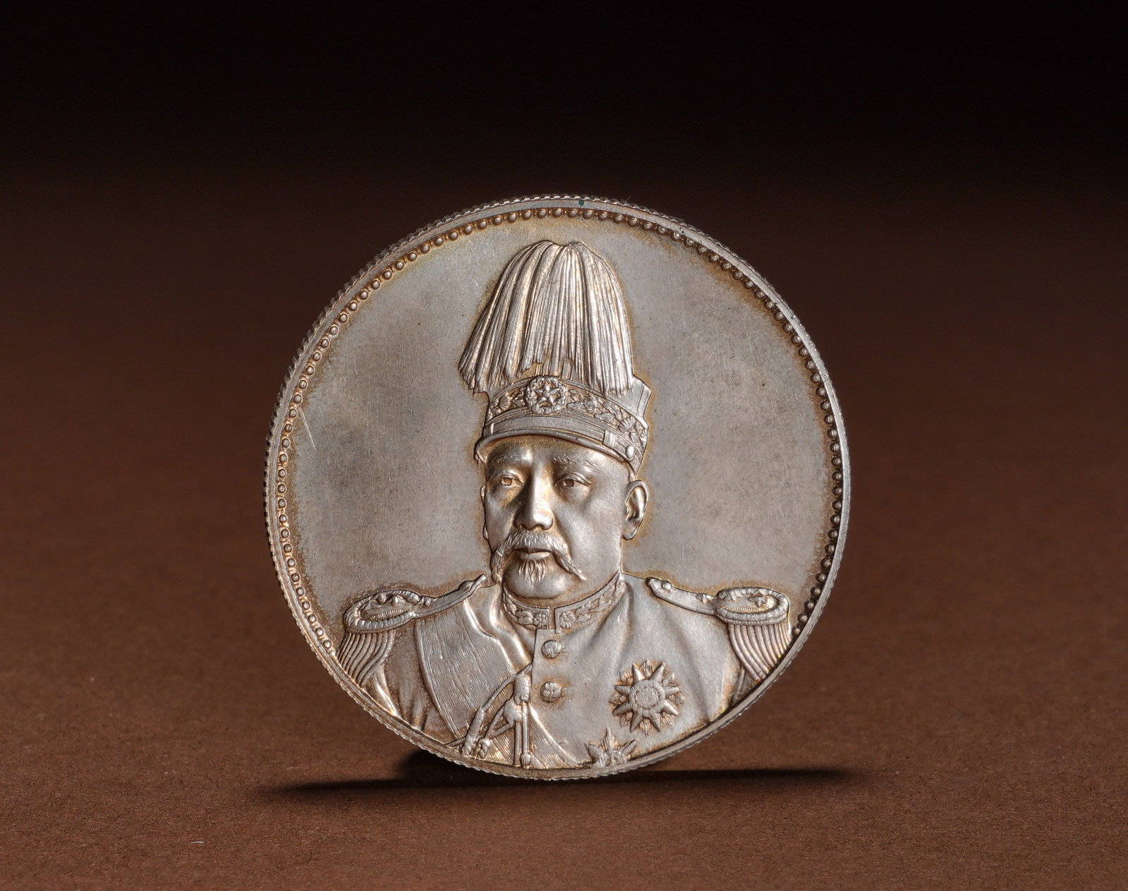 YUAN SHIKAI HONG XIAN ERA FLYING DRAGON COMMEMORATIVE SILVER COIN: Diameter:3.9cmWeight:27gHongxian Era Flying Dragon commemorative silver dollar of Yuan Shikai, minted in silver. The obverse features a bust portrait of Yuan Shikai in marshal uniform with a tall