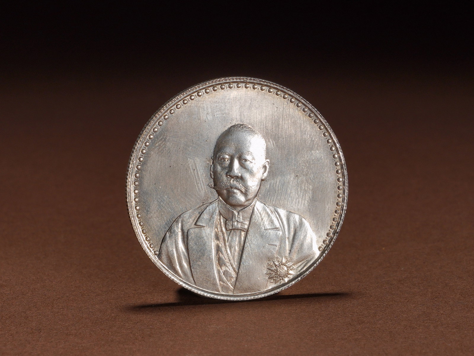 SILVER COIN COMMEMORATING THE ESTABLISHMENT OF THE CONSTITUTION BY CAO KUN IN THE 12TH YEAR OF THE: Diameter:3.9cmWeight:27gSilver commemorative coin for the Establishment of the Constitution featuring Cao Kun in formal western suit, minted in the 12th year of the Republic of China. The obverse bear