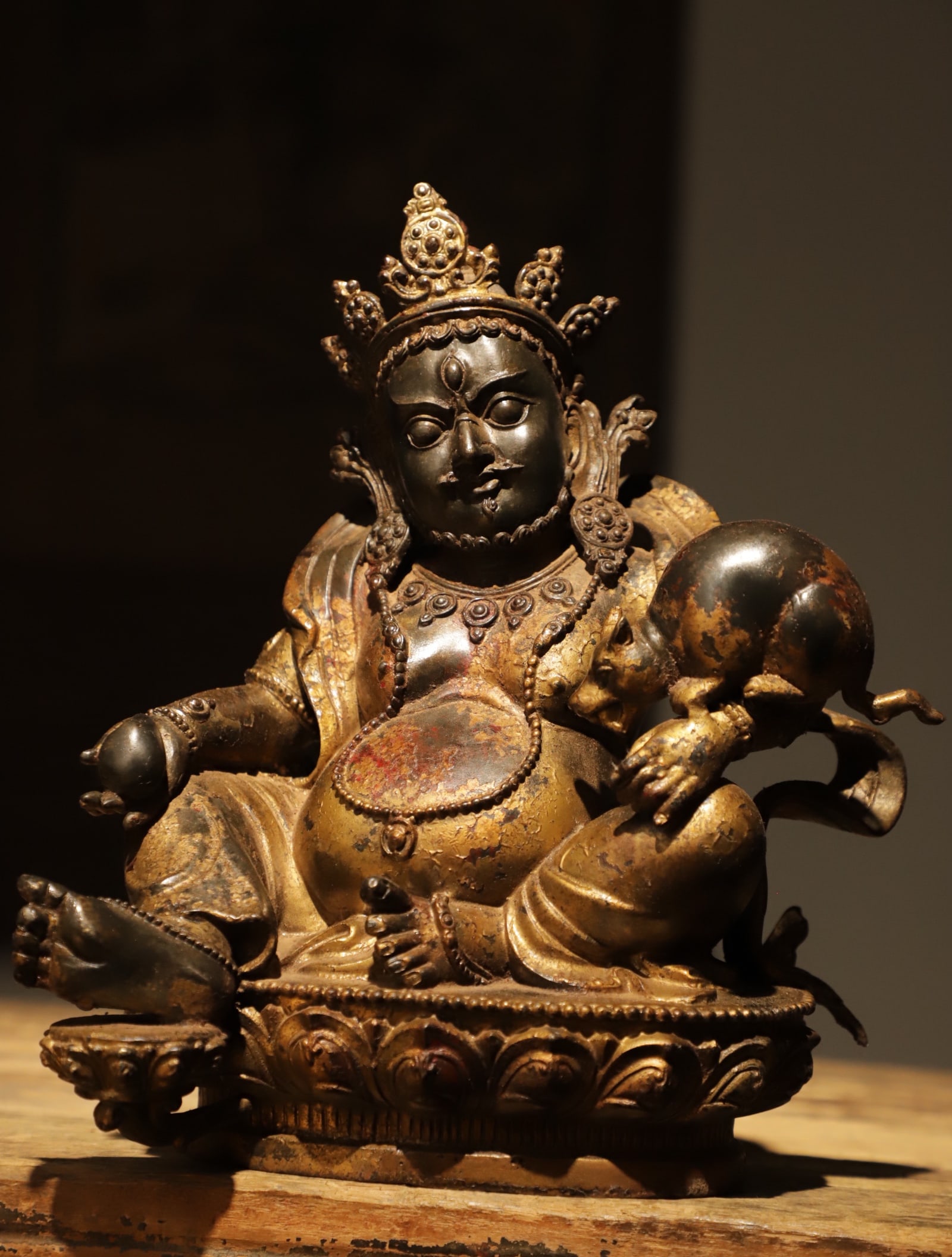 YUAN DYNASTY GILDED BRONZE SEATED STATUE OF THE YELLOW GOD OF WEALTH: Height:26cm(10.24in) Width:21cm(8.27in) Weight:3600g(7.94lb)Antique Tibetan gilt bronze Yellow Jambhala, holding treasure mongoose and mani pearl, lotus base, worn gilded surface, deity for wealth and
