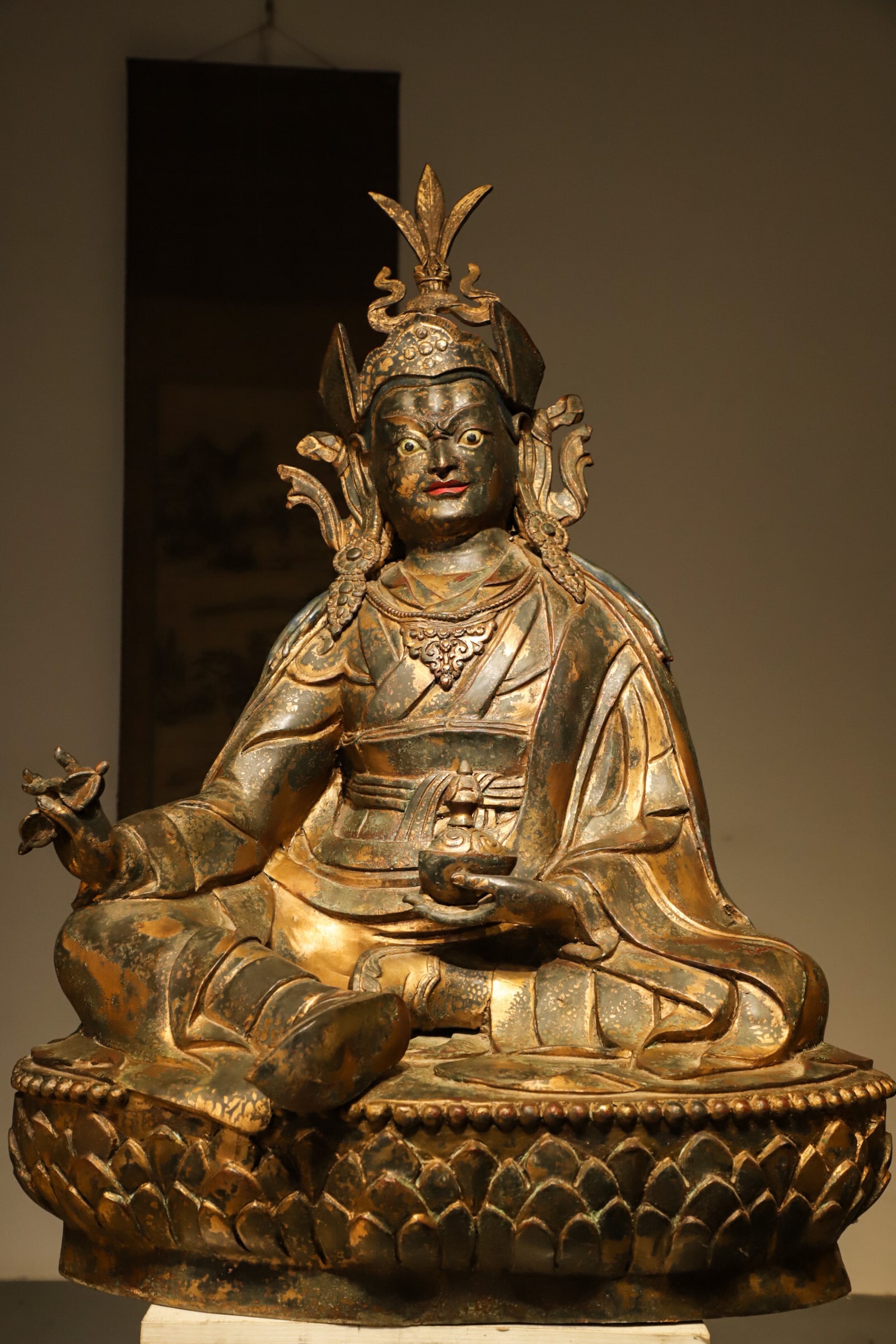 A GILDED BRONZE STATUE OF PADMASAMBHAVA FROM THE YUAN DYNASTY: Height:100cm(39.37in) Width:70cm(27.56in) Weight:38800g(85.54lb)Antique Tibetan gilt bronze Padmasambhava statue, seated on lotus base with vajra and kapala, worn gilding, symbolizing spiritual delive