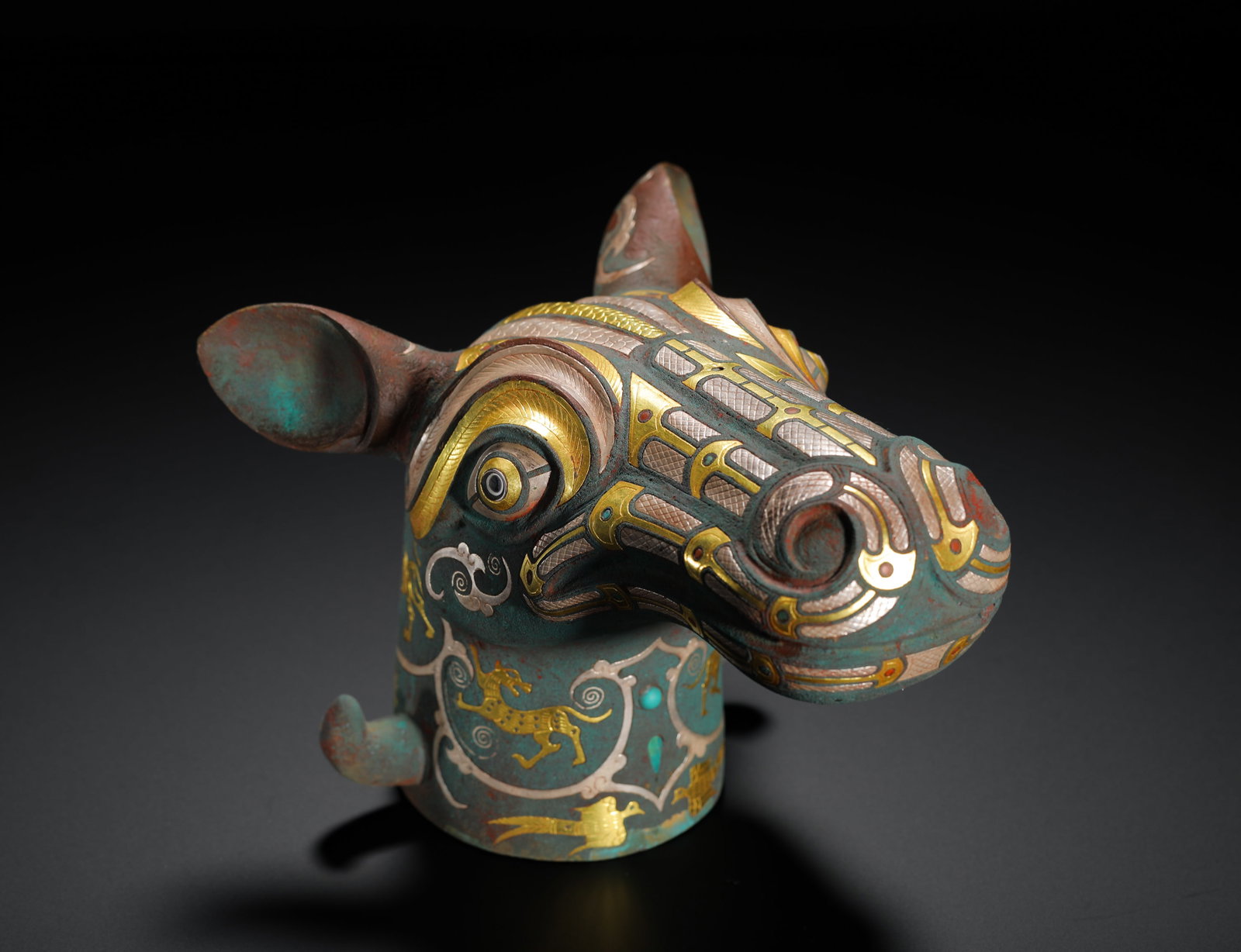 BRONZE HORSE HEAD WITH INLAID GOLD AND SILVER INLAID AUSPICIOUS BEAST PATTERN FROM THE WARRING: H:17cm (6.69in) W:21cm (8.27in) Weight:1260g (2.78lb)Bronze chariot end cap shaped as horse head, inlaid gold-silver beasts & turquoise, ancient gilt inscription inside socket.