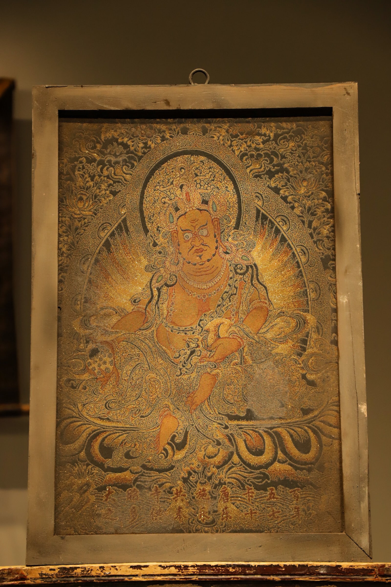 OLD SILK THANGKA OF THE QING DYNASTY ? YELLOW GOD OF WEALTH: Height:65cm(25.59in), Long:46cm(18.11in)Set in vintage wooden frame and crafted by brocade weaving. Yellow Jambhala sits in relaxed posture, adorned with crown and ornaments, holding a treasure