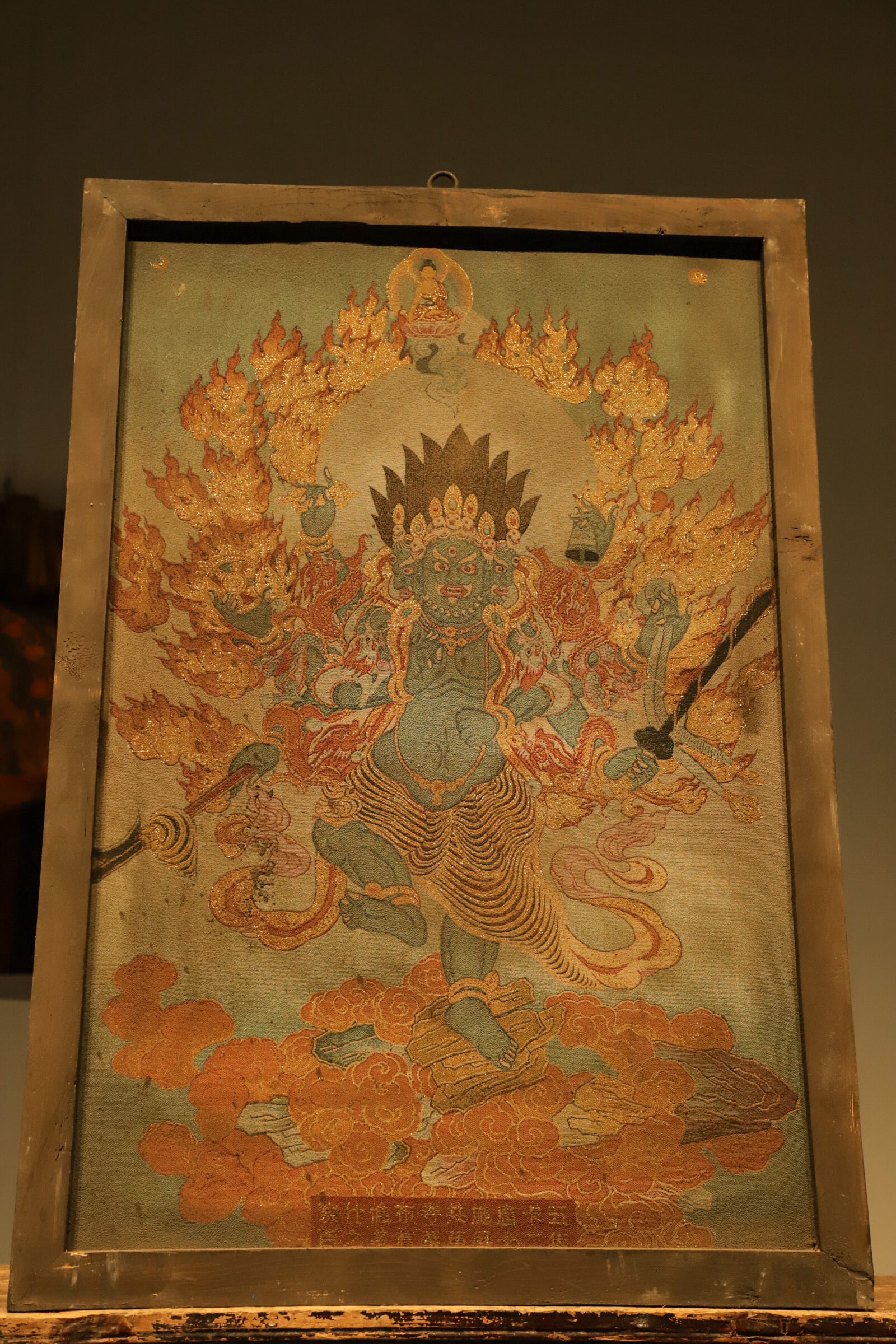 OLD THANGKA MADE OF SILK FROM THE QING DYNASTY ? VAJRA WITH DEFILEMENT: Height:96cm(37.80in), Long:66cm(25.98in)Mounted in vintage wooden frame and crafted by delicate brocade weaving. The three-headed multi-armed Vajra appears in wrathful form, holding various ritual imp