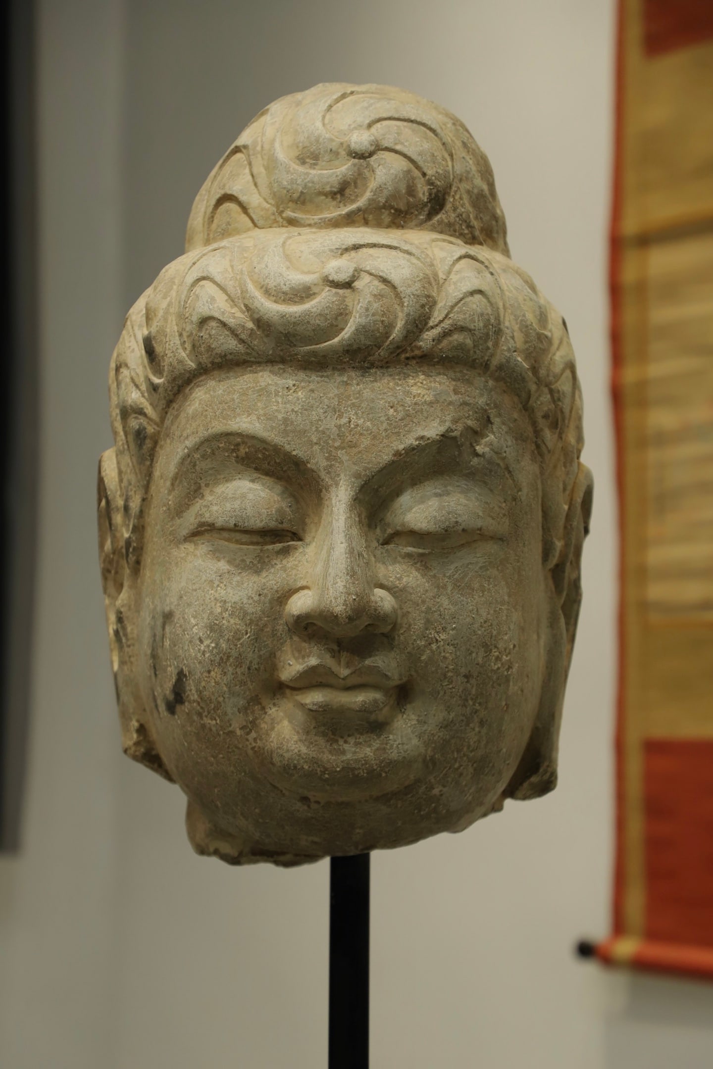 STONE BUDDHA HEAD STATUES FROM THE SUI DYNASTY: With base Height:88cm(34.65in), Height:50cm(19.69in), Long:35cm(13.78in), Width:30cm(11.81in)Made of stone in Sui Dynasty, with natural weathering traces. It has neatly coiled spiral hair, soft round 