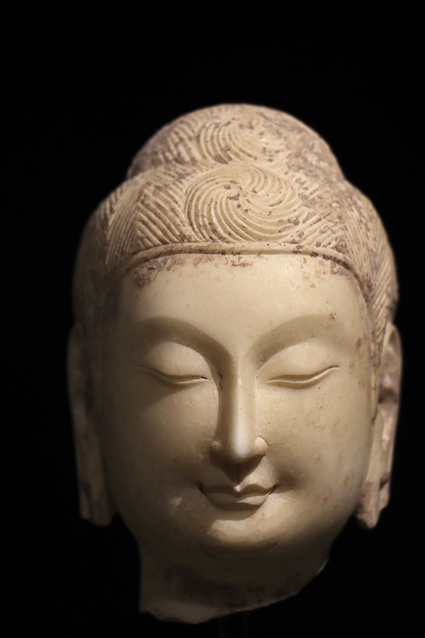 A WHITE MARBLE BUDDHA HEAD FROM THE NORTHERN WEI DYNASTY: Dimensions without base Height:14cm (5.51in)White marble Buddha head of Tang Dynasty, delicate spiral hair, serene gentle facial features, Chinese stone Buddhist carving.