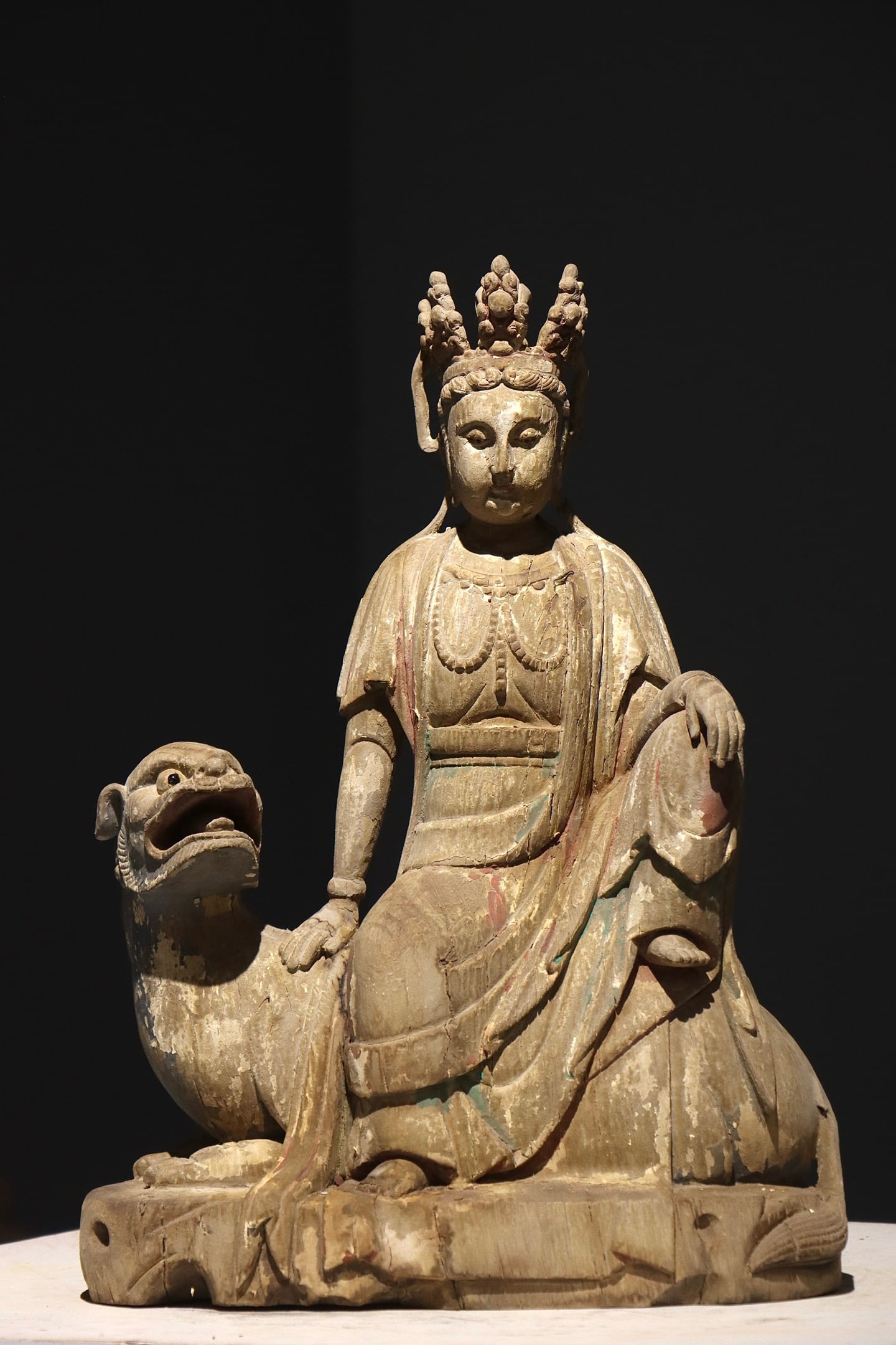 PAINTED MANJUSRI BODHISATTVA RIDING A LION FROM THE SONG DYNASTY: Height:48cm(18.90in), Width:35cm(13.78in)Wood painted statue of Manjushri Bodhisattva riding a lion. The Bodhisattva sits casually atop a recumbent lion, wearing an ornate crown with serene facial exp