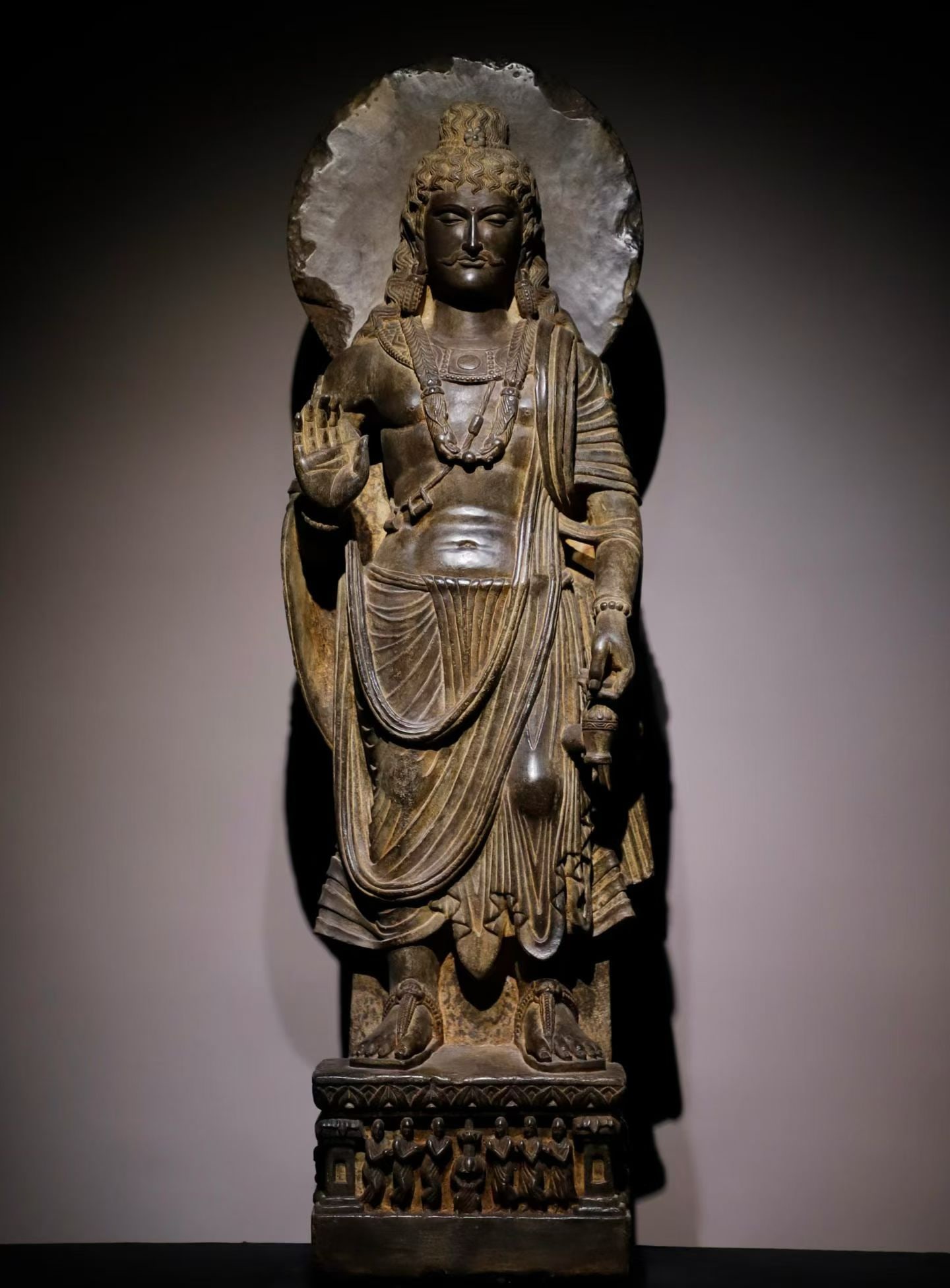 5TH-CENTURY STONE GANDHARA STATUE OF BODHISATTVA HOLDING A VASE: Height:128cm(50.39in), Width:42cm(16.54in), Thick:26cm(10.24in)Black stone standing Bodhisattva statue of Gandhara style. The Bodhisattva bears aristocratic features with curly hair and characteristic