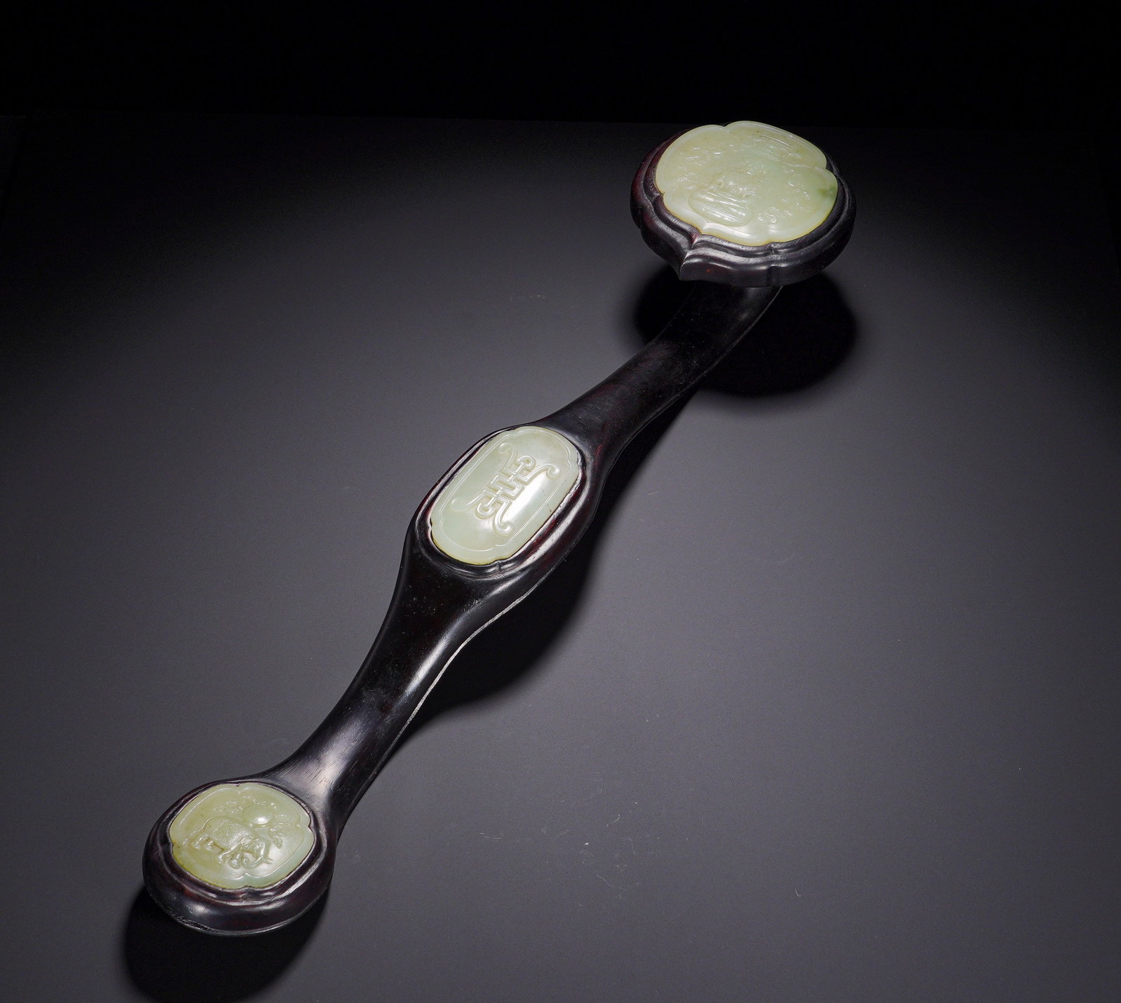QING DYNASTY PURPLE SANDALWOOD INLAID AND TIANQING WHITE JADE THREE-INLAID RUYI: Long:53cm (20.87in) , Width:12cm (4.72in) , Weight:760g (1.676lb) Carved from solid precious zitan wood with deep tone and mellow patina. The reverse side is fully incised with gilded imperial poems a