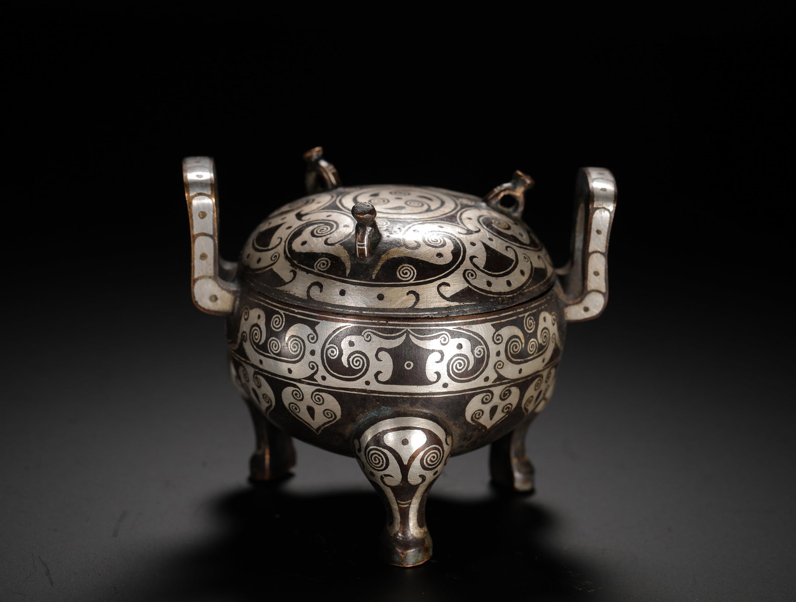 BRONZE INLAID SILVER TRIPOD OF THE WARRING STATES PERIOD: H:7.5cm (2.95in) W:9cm (3.54in) Weight:340g (0.75lb) This is a Warring States Period bronze ritual vessel. Decorated with intricate patterns inlaid with silver, it exemplifies the combination of super