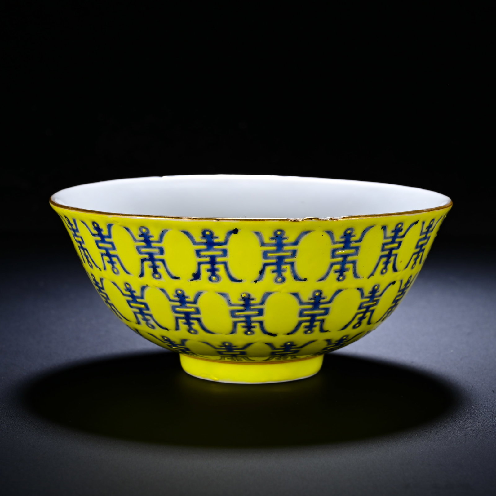 QING DYNASTY TONGZHI YELLOW GROUND BLUE COLOR LONGEVITY CHARACTER PATTERN BOWL: Height:5cm (1.97in) , Diameter:11.3cm (4.45in) Bowl with flared rim, curved belly and raised foot, gilt?trimmed rim. Exterior bright yellow ground densely covered with formal blue enamel seal?script