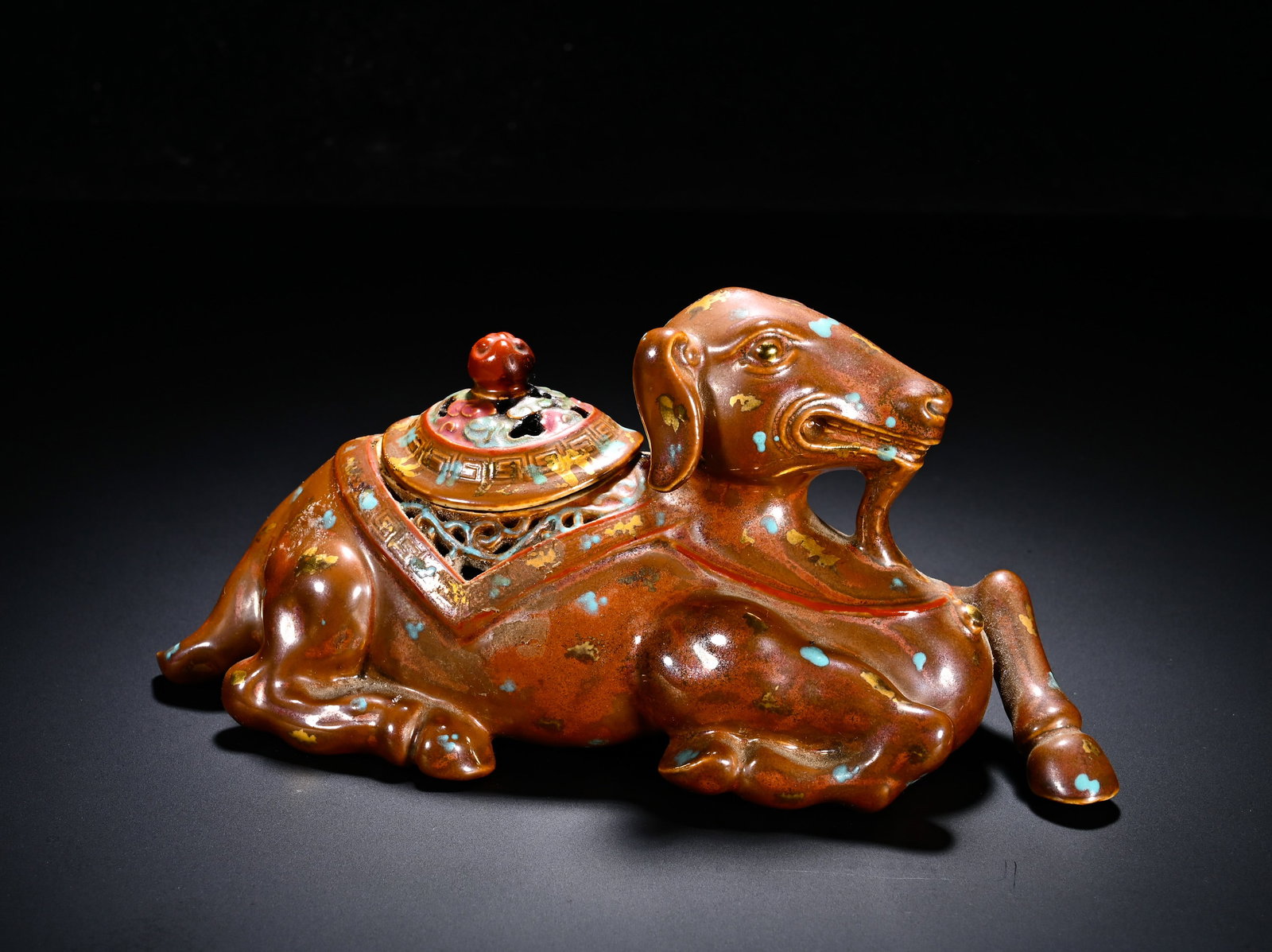 QING DYNASTY QIANLONG SAUCE GLAZE GILDED DOT COLOR LYING SHEEP INCENSE: Height:8cm (3.15in) , Width:18.5cm (7.28in) Fine porcelain censer modelled as a reclining goat holding a ling?zhi sprig in its mouth with plump rounded anatomy. Removable pierced?openwork lid sits on