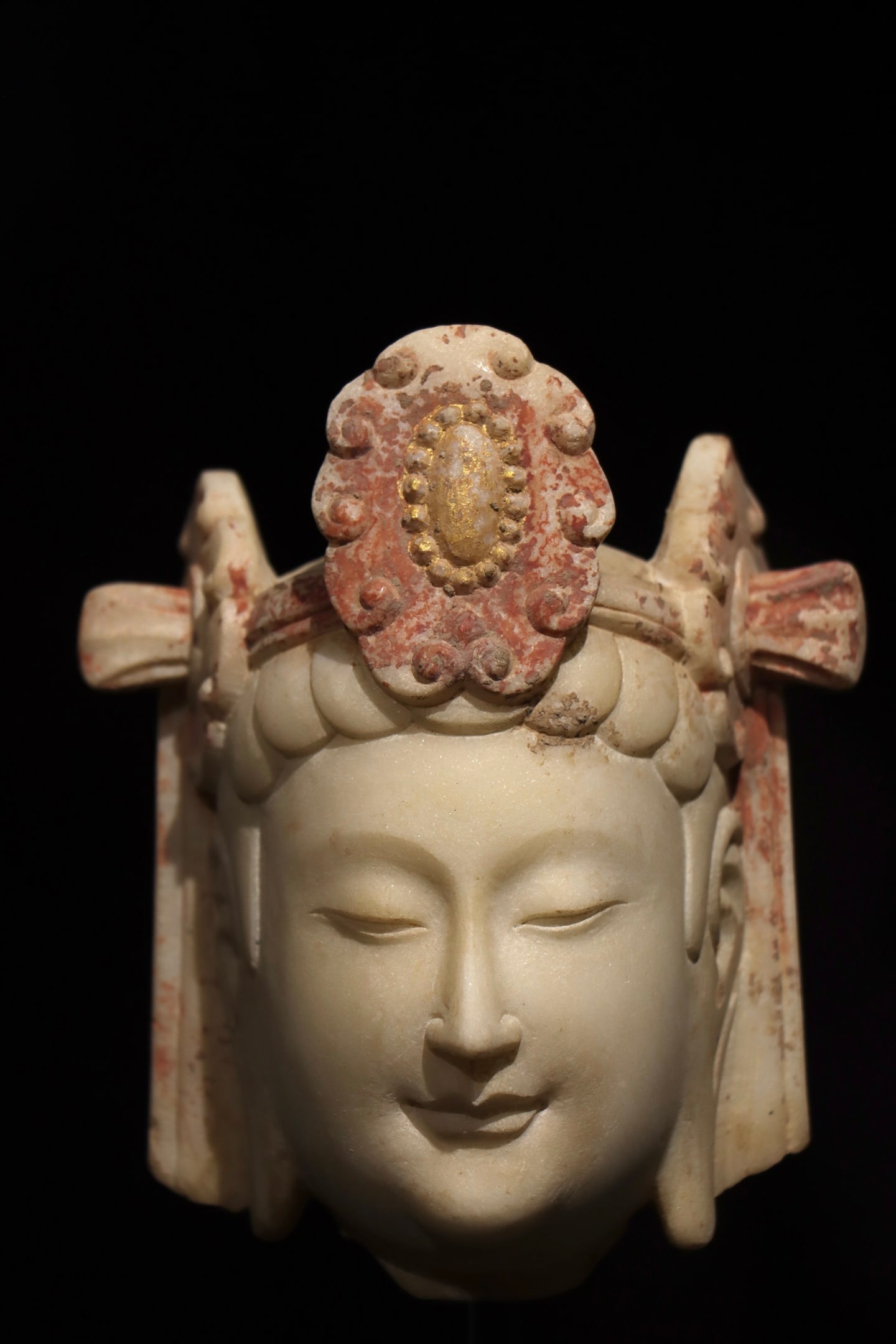 A WHITE MARBLE GUANYIN HEAD FROM THE NORTHERN QI PERIOD: Dimensions without base Height:14cm (5.51in) White marble Guanyin Bodhisattva head with gilded and red mineral pigment decoration, traditional Chinese stone Buddhist sculpture.
