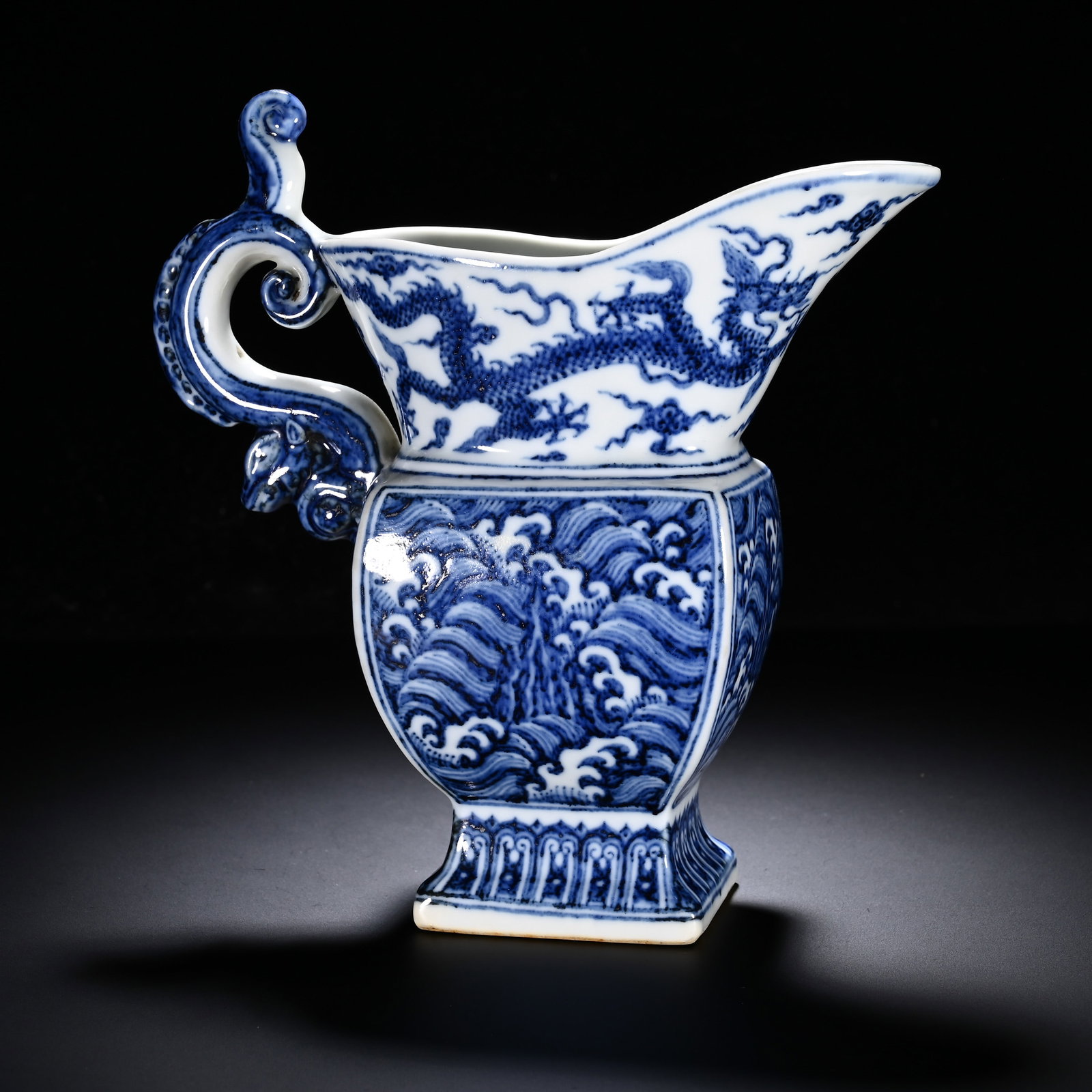 MING XUANDE BLUE AND WHITE WATER DRAGON PATTERNED FLOWER POT: Height:17cm (6.69in) , Width:15cm (5.91in) Modelled after archaic bronze gong vessel, with upturned spout, square?section body, square foot?ring and elaborate chi?dragon scroll?shaped handle. Spout?se