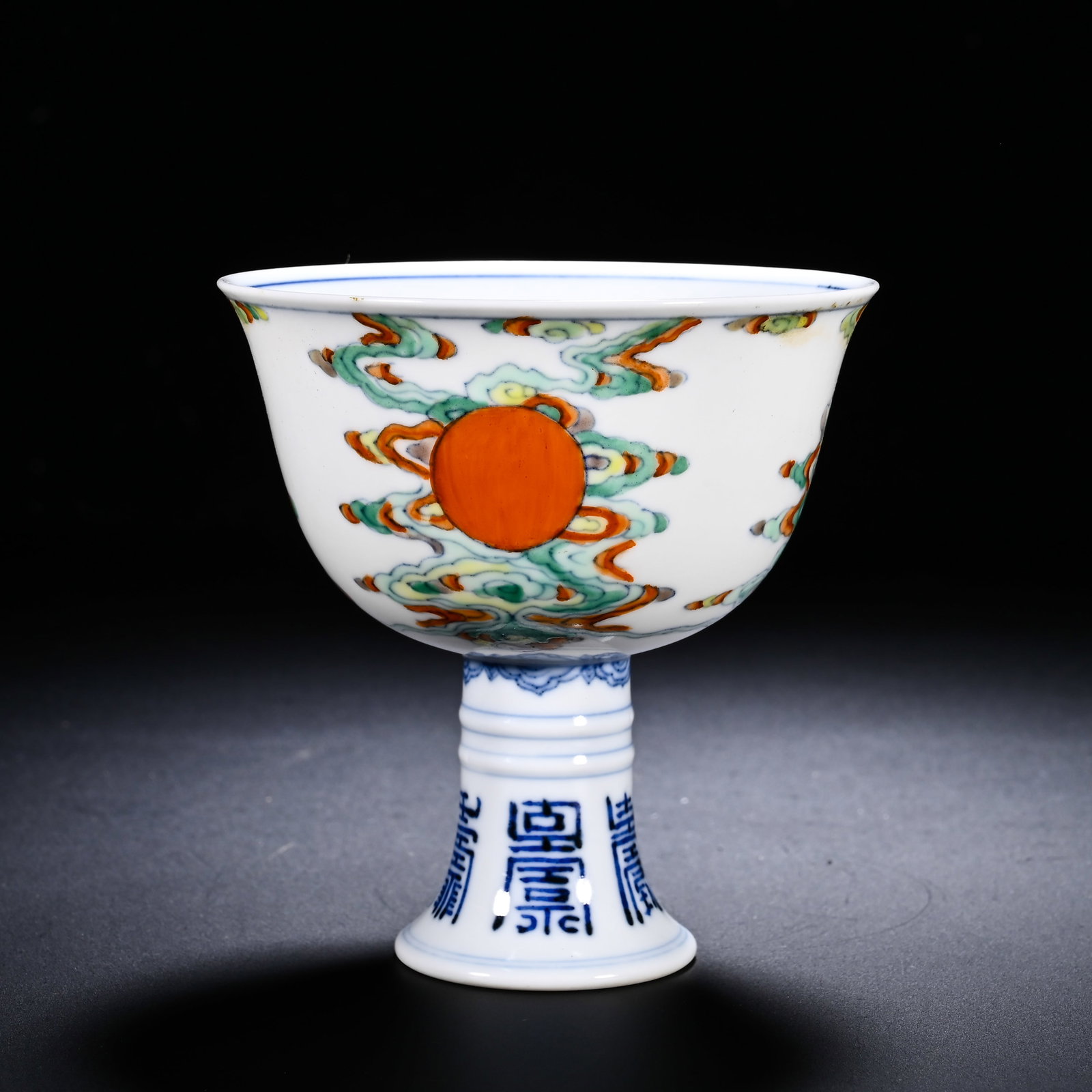 QING YONGZHENG DOUCAI CLOUD RISING SUN LONGEVITY CHARACTER PATTERN HIGH-FOOTED CUP: Height:8.5cm (3.35in) , Diameter:8.2cm (3.23in) Wide flared mouth, curved bowl body rising to a tall stem foot articulated with raised bow?string mouldings, a canonical Qing?dynasty stem?cup form. The
