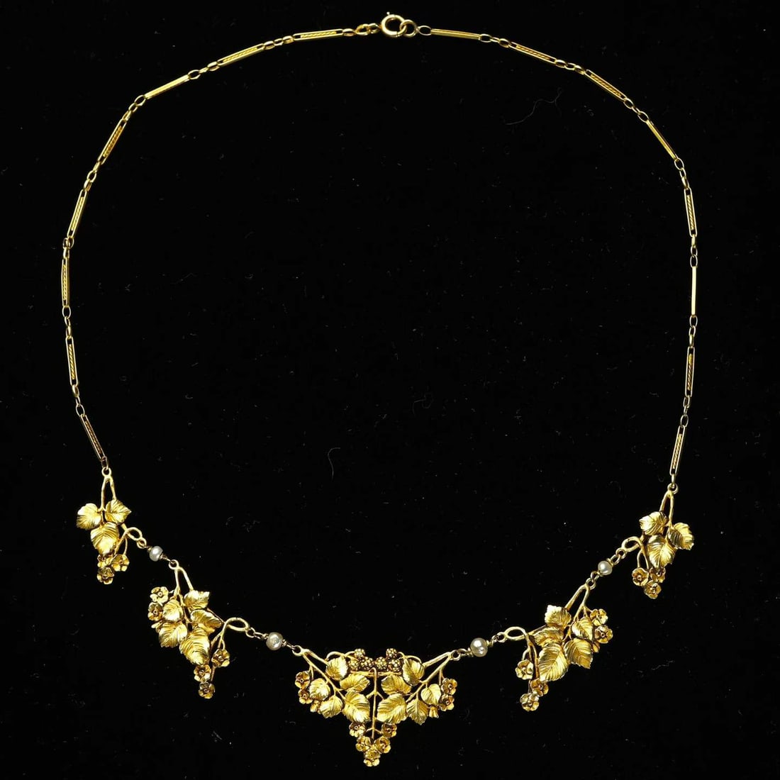 Art Nouveau (1880-1920) French 18K Gold Foliage and Drapery Necklace: Chain Length:43cm Wt:19.9g Entirely handcrafted in 18K gold with high-relief scrolling foliate motifs. The elegant lines of the golden blooms evoke a corner of a garden glistening with morning dew, em