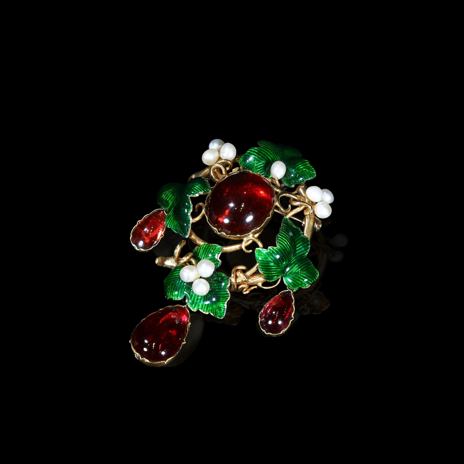 Victorian 18-Karat (750-standard) Gold Brooch, Naturalistic Grape-Vine Motif, Garnets, Green Enamel: 6.5*4.36cm Wt:22.22g Victorian naturalistic 750-standard (18-karat) gold drop-brooch. Centred with a large cabochon garnet. Vibrant green enamel forms grape-leaves; clusters of natural pearls represen