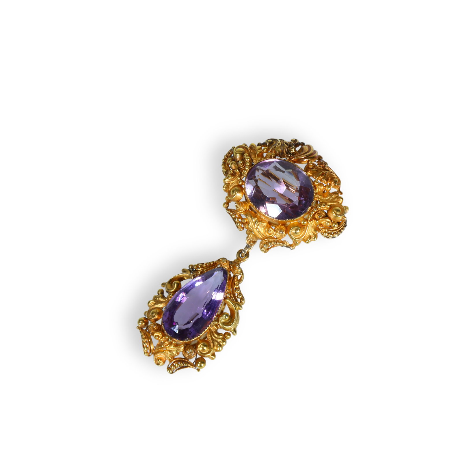 Victorian Rococo-Revival Gold Drop-Brooch set with Oval and Pear-Shaped Amethysts: 6.1*3.3cm Wt:12.61g Victorian gold drop-brooch of Rococo-Revival design with articulated swinging pendant. An oval-cut amethyst is set within an elaborate high-relief chased foliate scroll mount. Susp