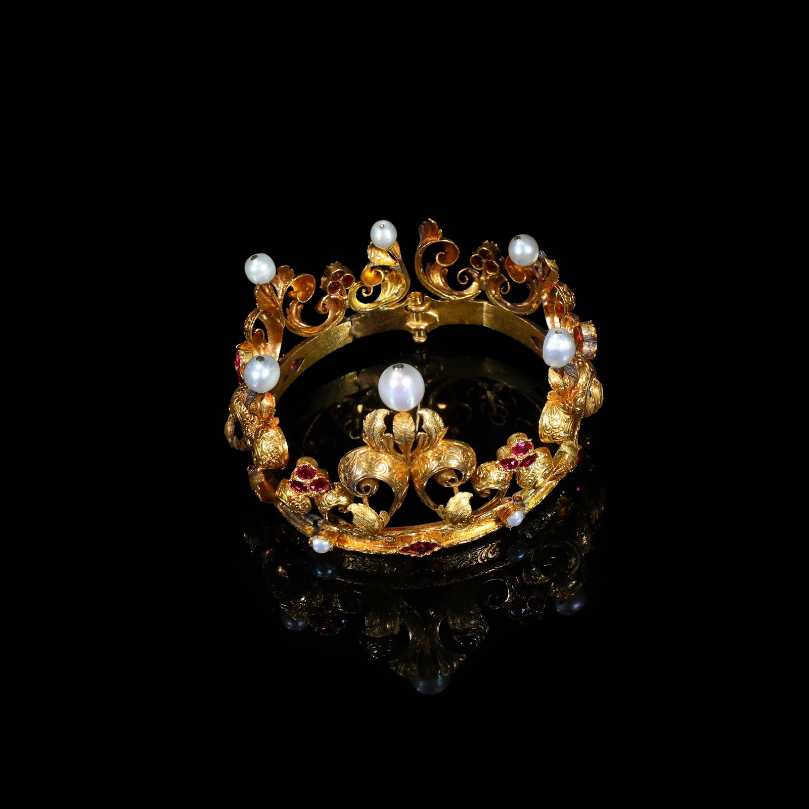 Victorian Gold Foliate Bracelet set with Pearls and Rubies: inner diameter:58mm Wt:37.14g Victorian gold foliate bangle-bracelet of open-work design. The circular hinged bangle is richly worked with swirling foliage and flower-bud motifs. Six prominent pearls 