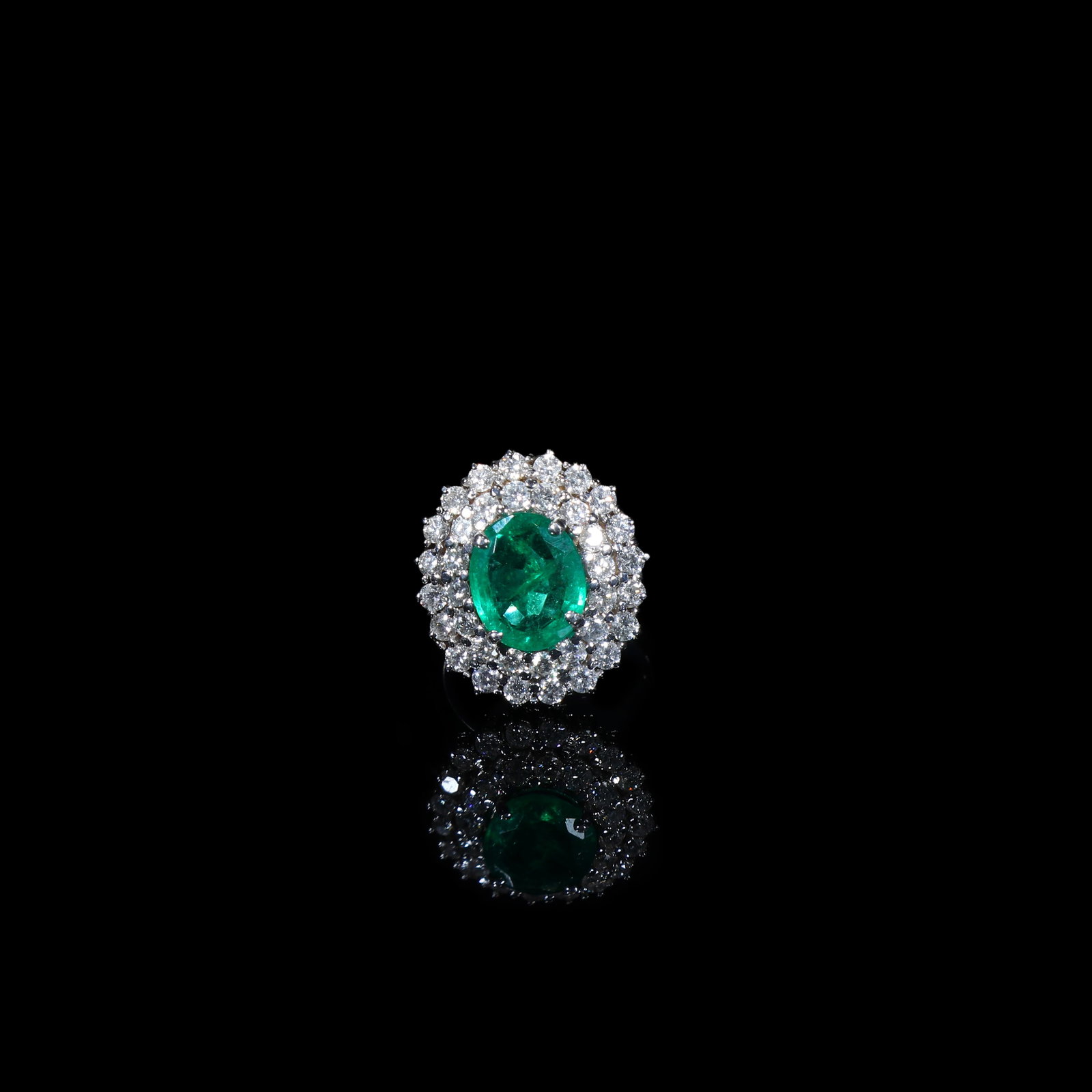 Edwardian Emerald Double-Cluster Diamond Ring, Platinum-Set, Circa 1880-1910: Ring Size: US 8 Wt:10.3g Edwardian ring, circa 1880-1910. Centring upon an oval-faceted emerald of rich vivid green colour, encircled by a double cluster of diamonds in a halo arrangement. Mounted in 