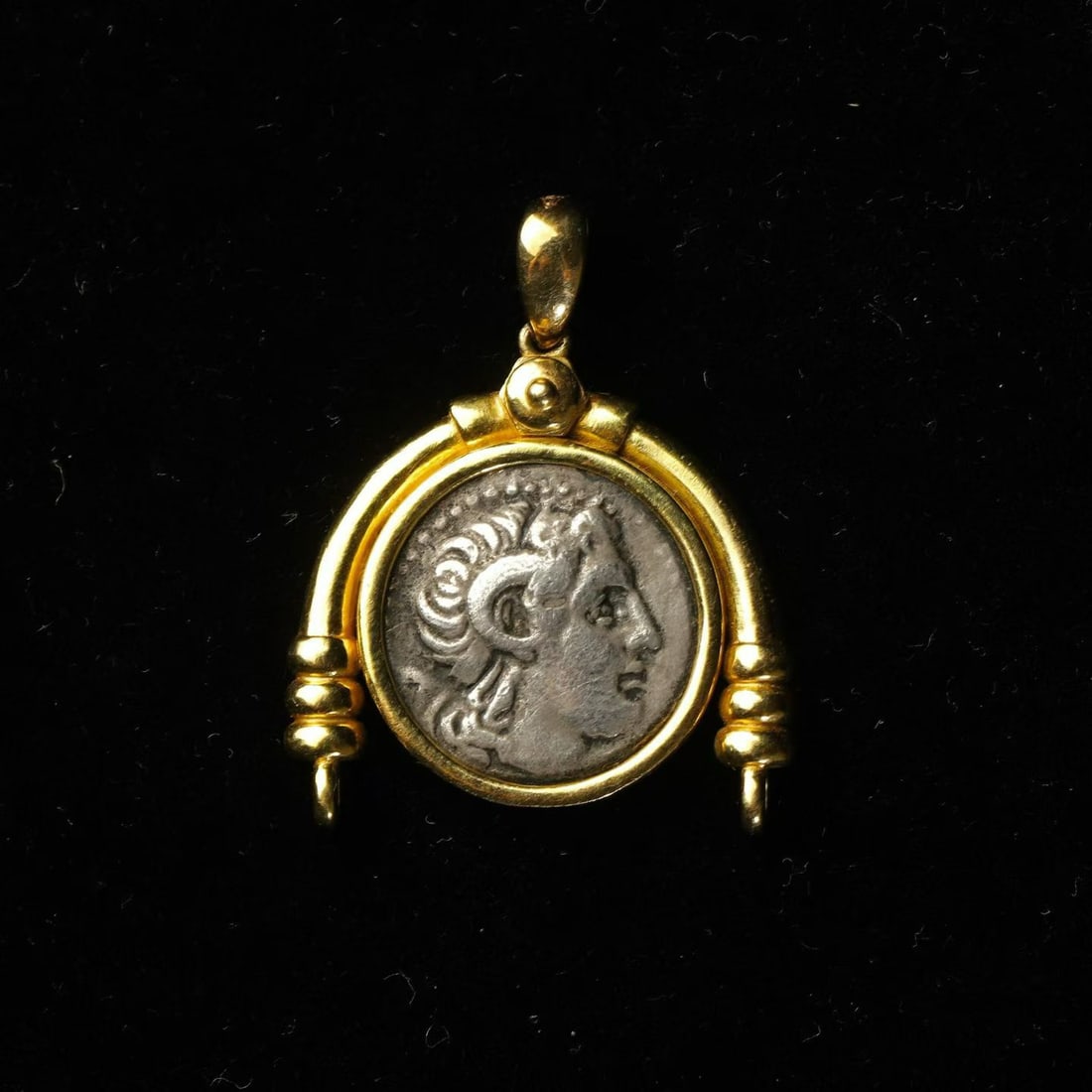 18K Gold Pendant with Ancient Greek Coin of Alexander the Great: L:3.4cm W:2.7cm Wt:8.25g Obverse: Alexander the Great with ram's horns.Reverse: Athena wearing an Attic helmet, seated upon a throne. In one hand she holds Nike bearing a wreath, while the other rests