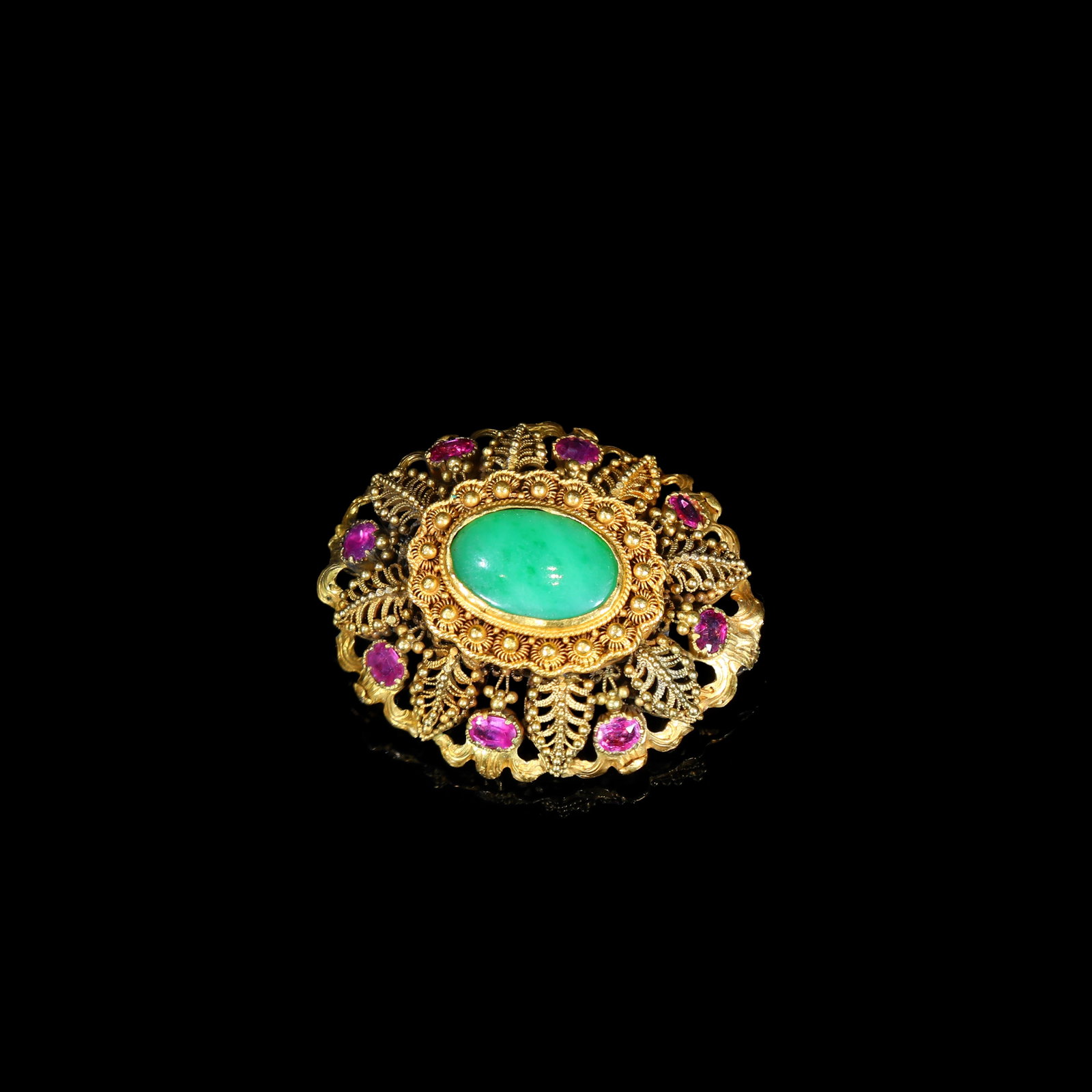 19th-Century Indian-Style Filigree Gold Brooch, Central Jadeite Cabochon with Ruby Accents: 3.35*4cm Wt:17.8g 19th-century filigree gold brooch of oval form, in Indian-jewellery taste. Centred by a large bezel-set jadeite cabochon, surrounded by multi-layer foliate open-work framework execut