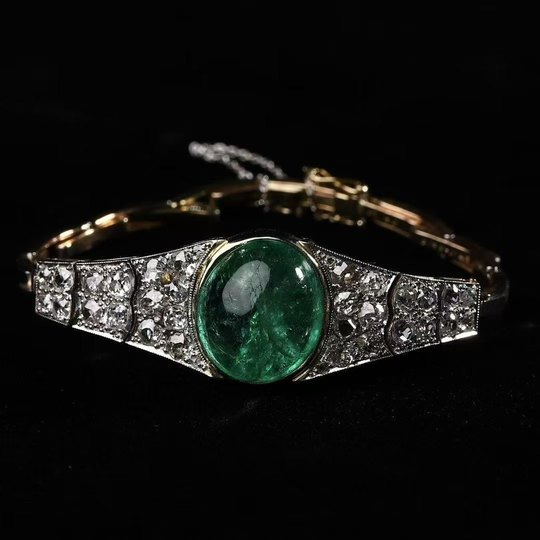 Art Deco Period (1925-1935) British Aristocrat Custom Two-Tone Gold Emerald and Diamond Bracelet: Bracelet Length:17.8cm Wt:18.1g Hand-fabricated chain with a 15K gold base overlaid with platinum. The centrepiece is a 15-carat Muzo Colombian emerald, serving as the visual focal point. 7 carats of 