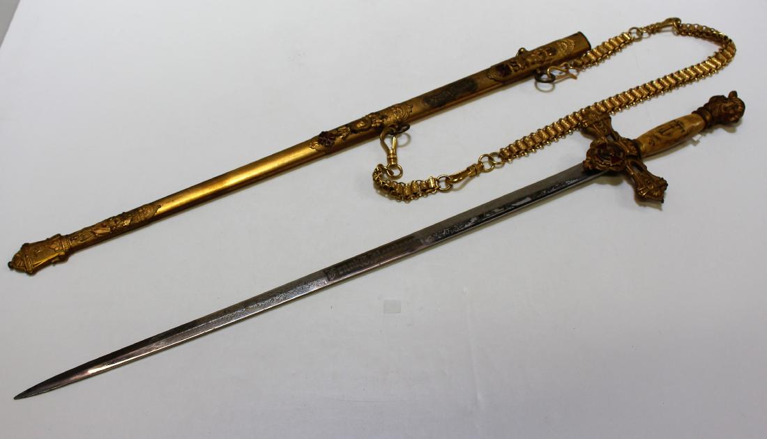 ELABORATE MASONIC CEREMONIAL SWORD & SCABBARD: Masonic Sword, with ivorine grip and enamel, and a beautiful scabbard that includes a gold tone belt sword chain. Enamel emblem with "In hoc signo vinces" - Engraved on the blade "Frank T. Hessinger"