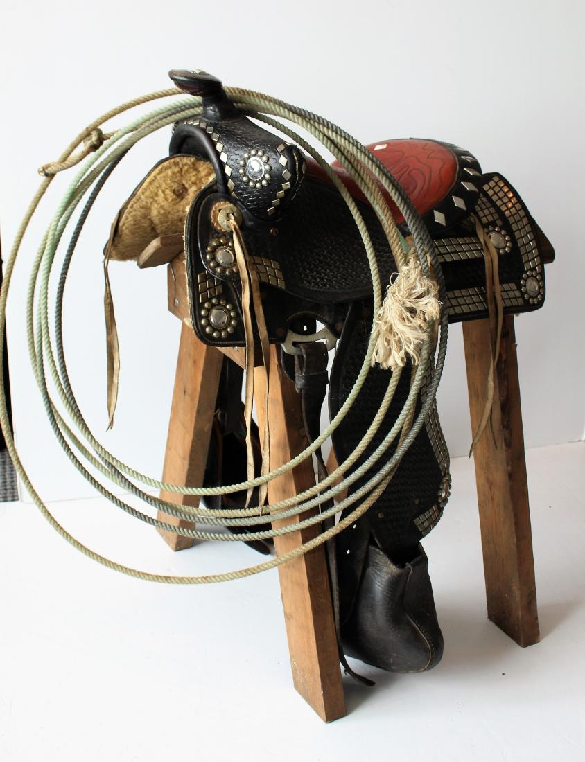 WESTERN SHOW SADDLE: Western show/parade saddle. Leather and silver mounts with hand tooling. Padded. And in good condition. With a lariat.