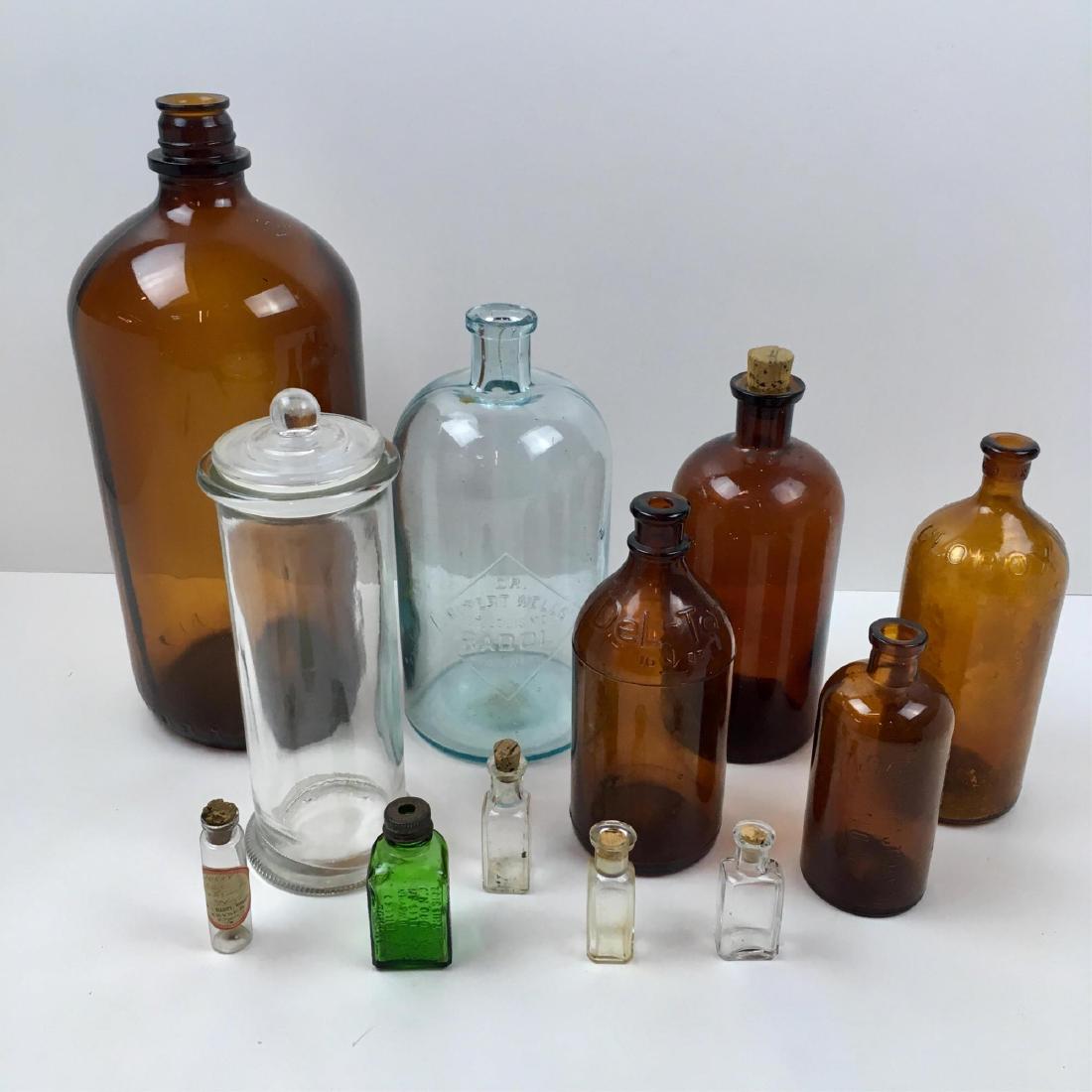 12 VINTAGE / ANTIQUE BOTTLES: 5 amber brown - 13.5", 8", 7.75" Clorox, 7" Del-Tox, 5.25" Frontier Asthma Co; 9.5" E. Rupert Wells Radol antique bottle ca. 1905-1910, 9.5" druggist's lidded canister, 3" green glass Antrol Ant Kille