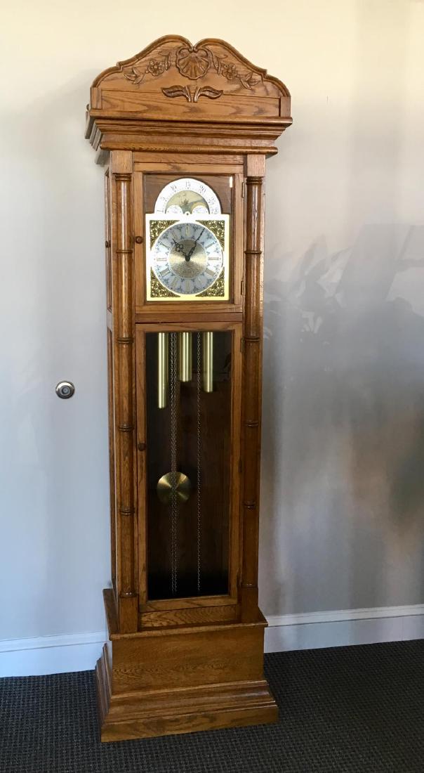 HERITAGE OAK TALL CASE CLOCK: Includes weights, pendulum and key - dial is marked "Heritage" (possibly mfr'd by Howard Miller?) - movement is marked Urgos Made in Germany 1054128 - measures 21.75" l 13.5" w x 79.5" h - not tested