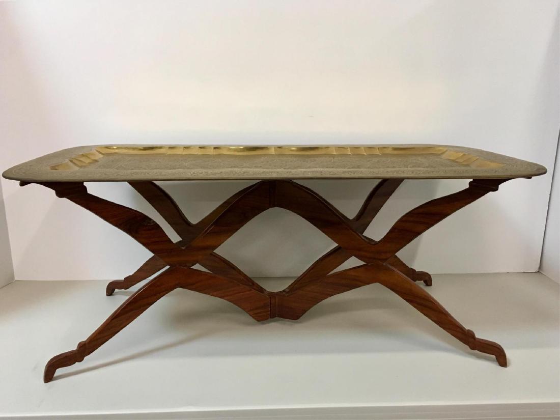 MIDDLE EASTERN STYLE BRASS COFFEE TABLE: Hand hammered brass tray with hand chased design on folding wood stand - 47.25" x 22.75" 18.25"