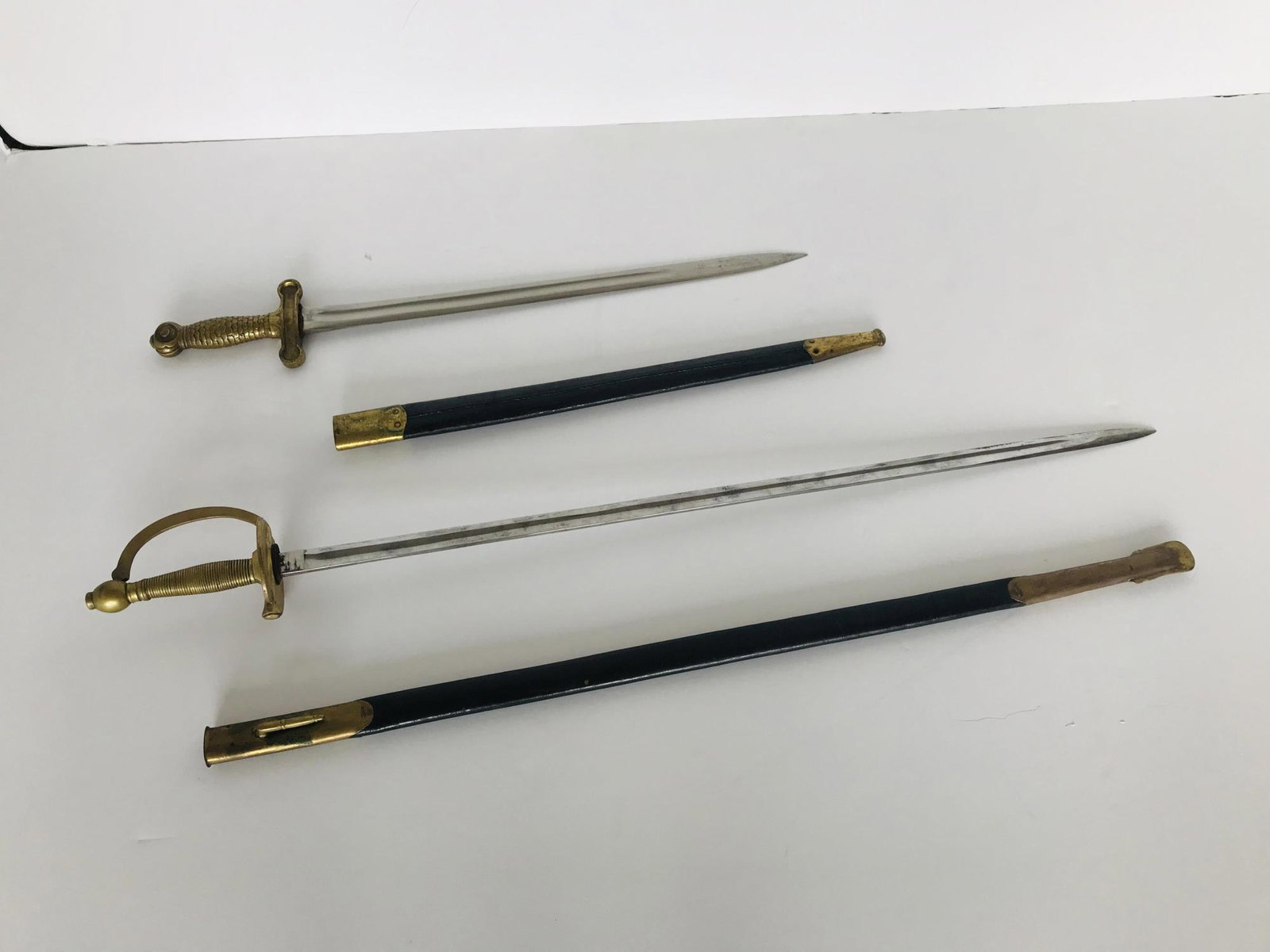 PAIR OF SWORDS & SHEATHS: Shortest 26" long has "USN CGS 1871" on the blade. Handle has a reptilian scale design. Longest is 37" and has had the makers marks rubbed off - In the style of a non-com officers sword. Good conditio