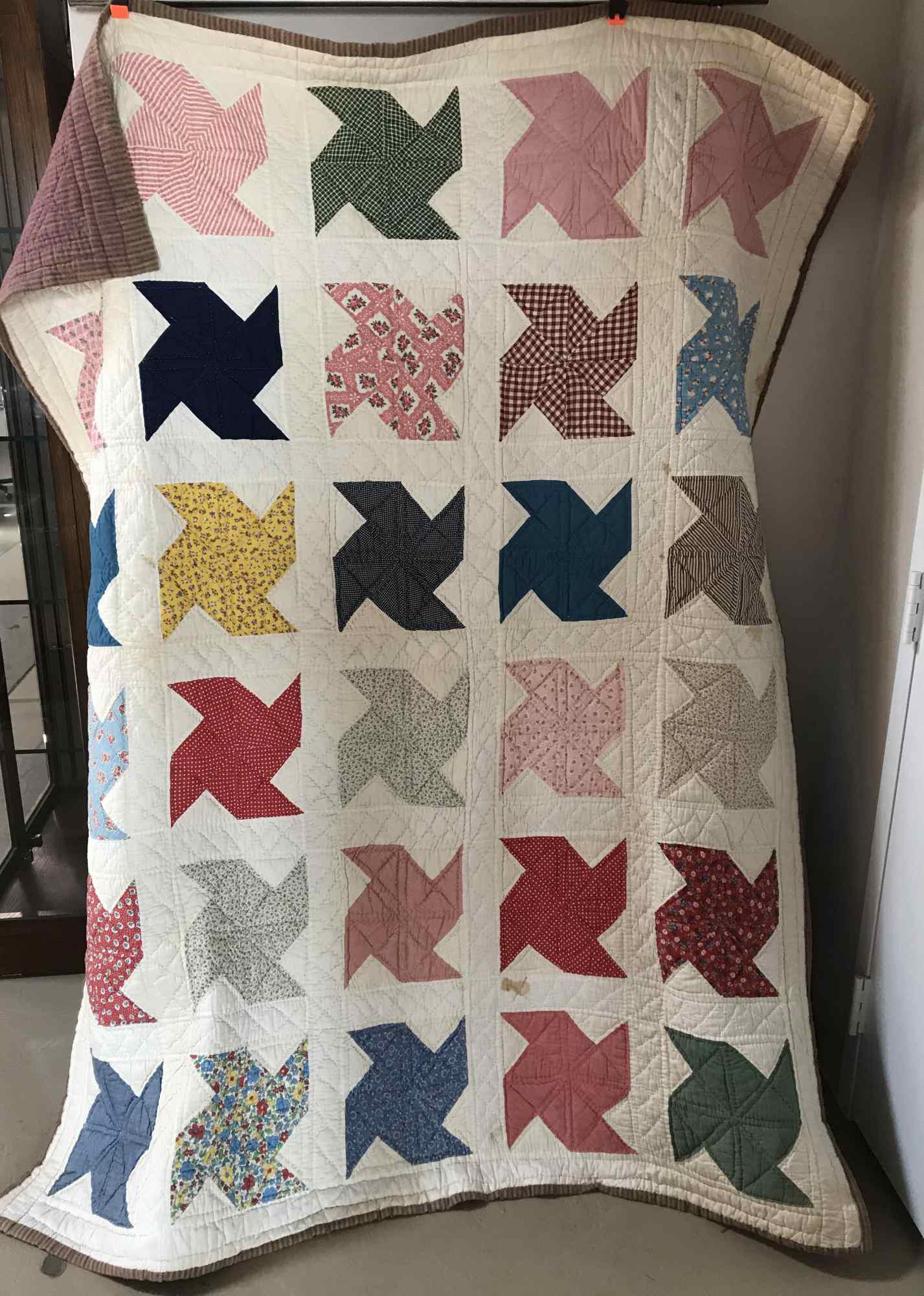 VINTAGE HANDMADE PINWHEEL QUILT: white with multi colored pinwheel pattern with minor staining - striped pink, purple and beige back , faded on edges and in large areas, 63" x 78"