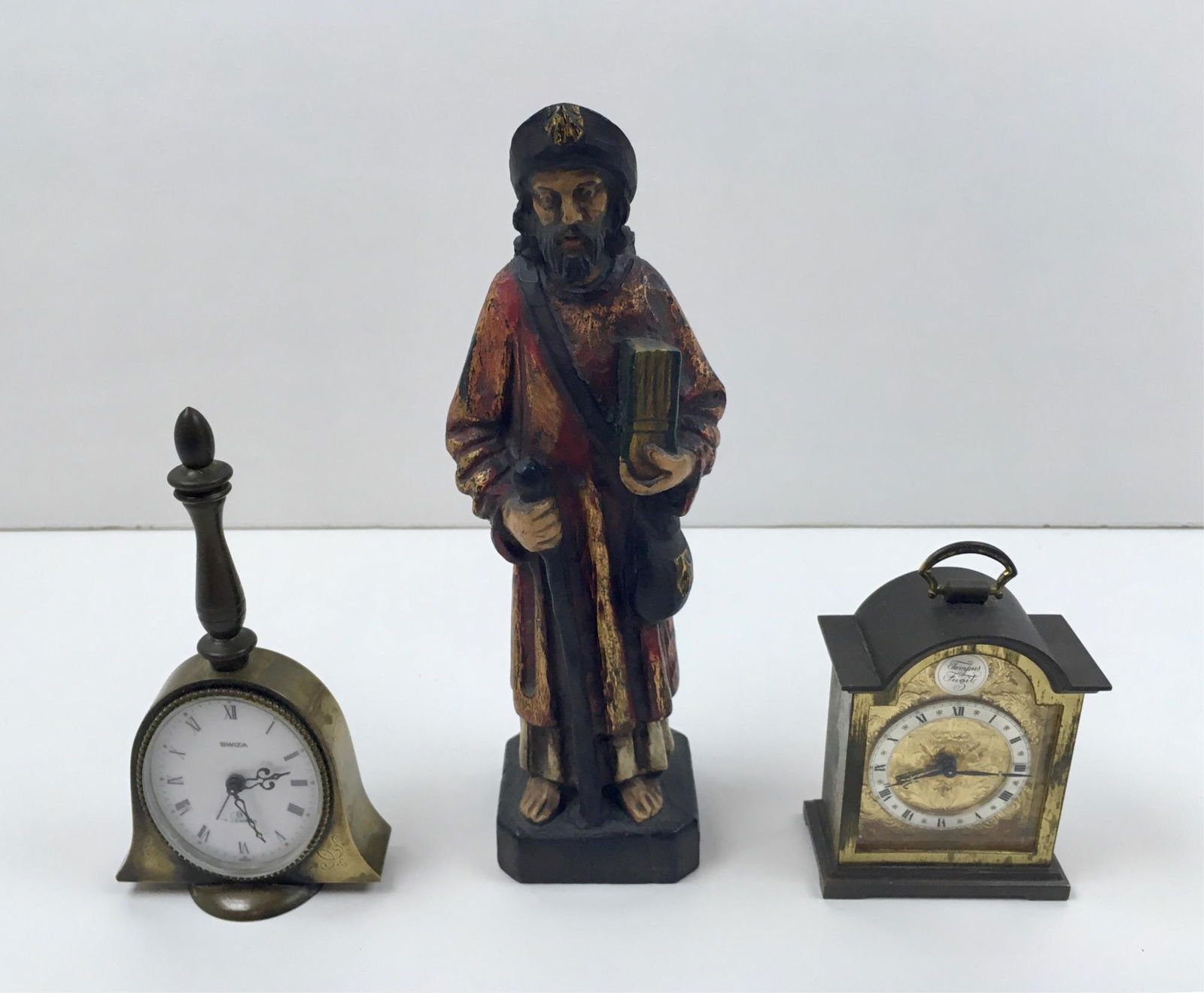 3 PCS - CLOCKS AND CARVED STATUE: Antique carved wood painted figure with book and walking stick, vintage 7 jewel small brass bell shaped alarm clock by Swiza in working condition 5.75" tall, vintage carriage clock by Swiza Sheffield