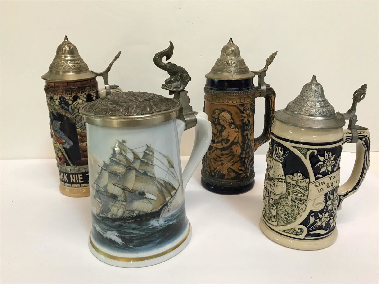 FOUR GERMAN BEER STEINS: 1 Original King stein with lidded top -message "never drink too much, happy beer we love" measures 10.5", 1 collectors tankard by L.H.Pearce is an original work crafted in fine porcelain by Haviland o