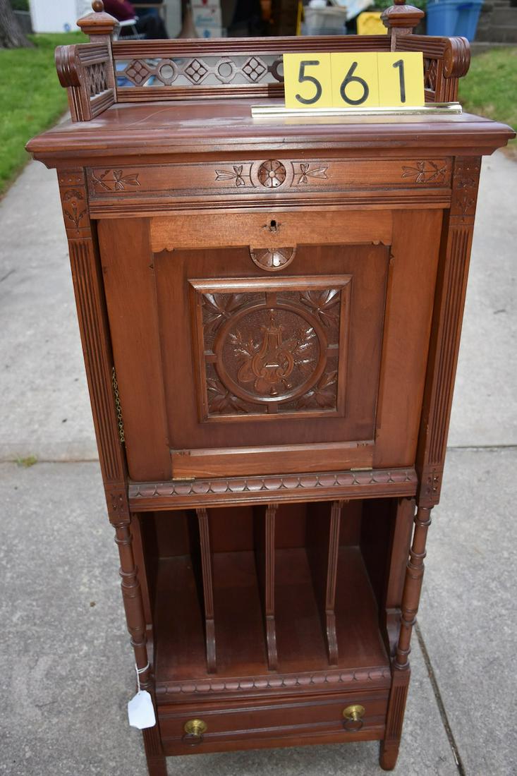 Eastlake Cherry Record and Sheet Music Cabinet: Has incised carving. Divided base record storage, drawer, and drop-door. The cabinet has a gallery. A good example. There are two cracks in the base of the drop door near the hinges