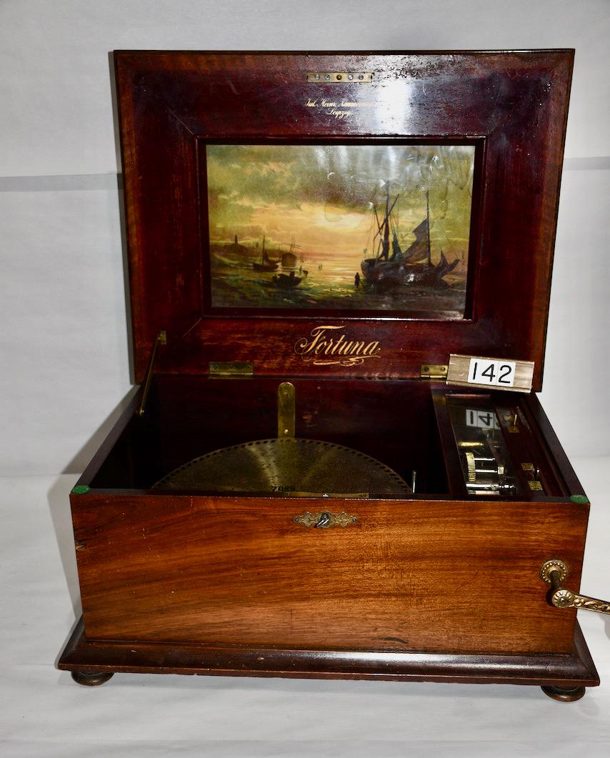 Fortuna Disc Music Box: Original Lithograph in the lid or cover. Plays a 14-5/8" disc. Inlaid top with floral decoration. Includes the crank. There are 13 discs included. Has crank. No broken teeth. Ca. 1900. Cabinet measure