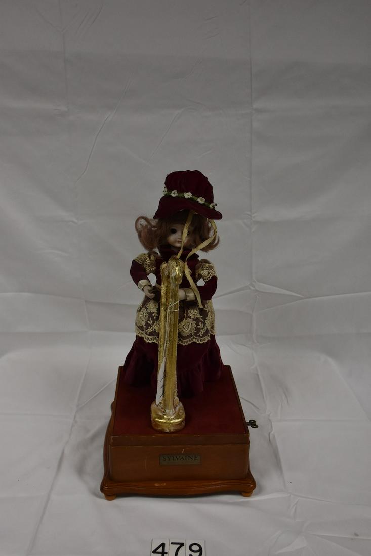 Modern Automaton with Doll and Harp: The music box appears to have a broken spring. The music box tries to play. Tag on the front is Sylvaine, The Jewels of the Madonna. 17" tall on a 9" square base