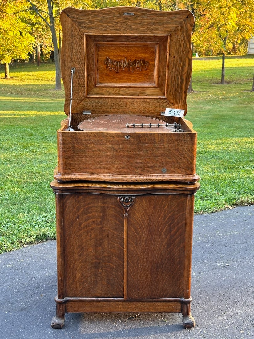 Oak Reginaphone 20-3/4" Disc Music Box: Serpentine oak case with matching oak base cabinet, Columbia tonearm, turntable. 9 Panel Nickel Horn. 17 20-3/4" music discs included