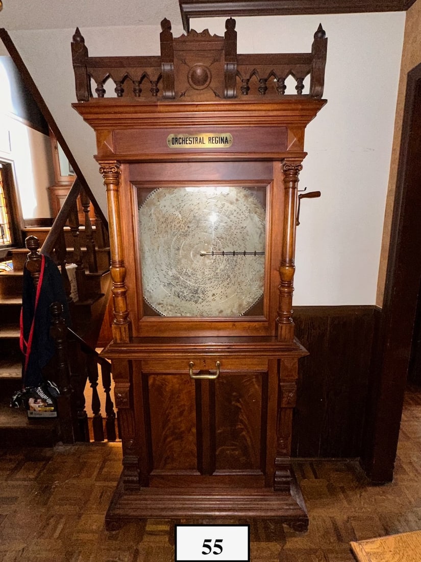 Regina Orchestral Upright Disc Music Box. Style 5: Coin operated. Plays a 27" disc. Excellent condition. Double comb with no broken teeth. Base tilt forward storage for discs. Mahogany cabinet. 9 discs are included. The gallery is not original to the 
